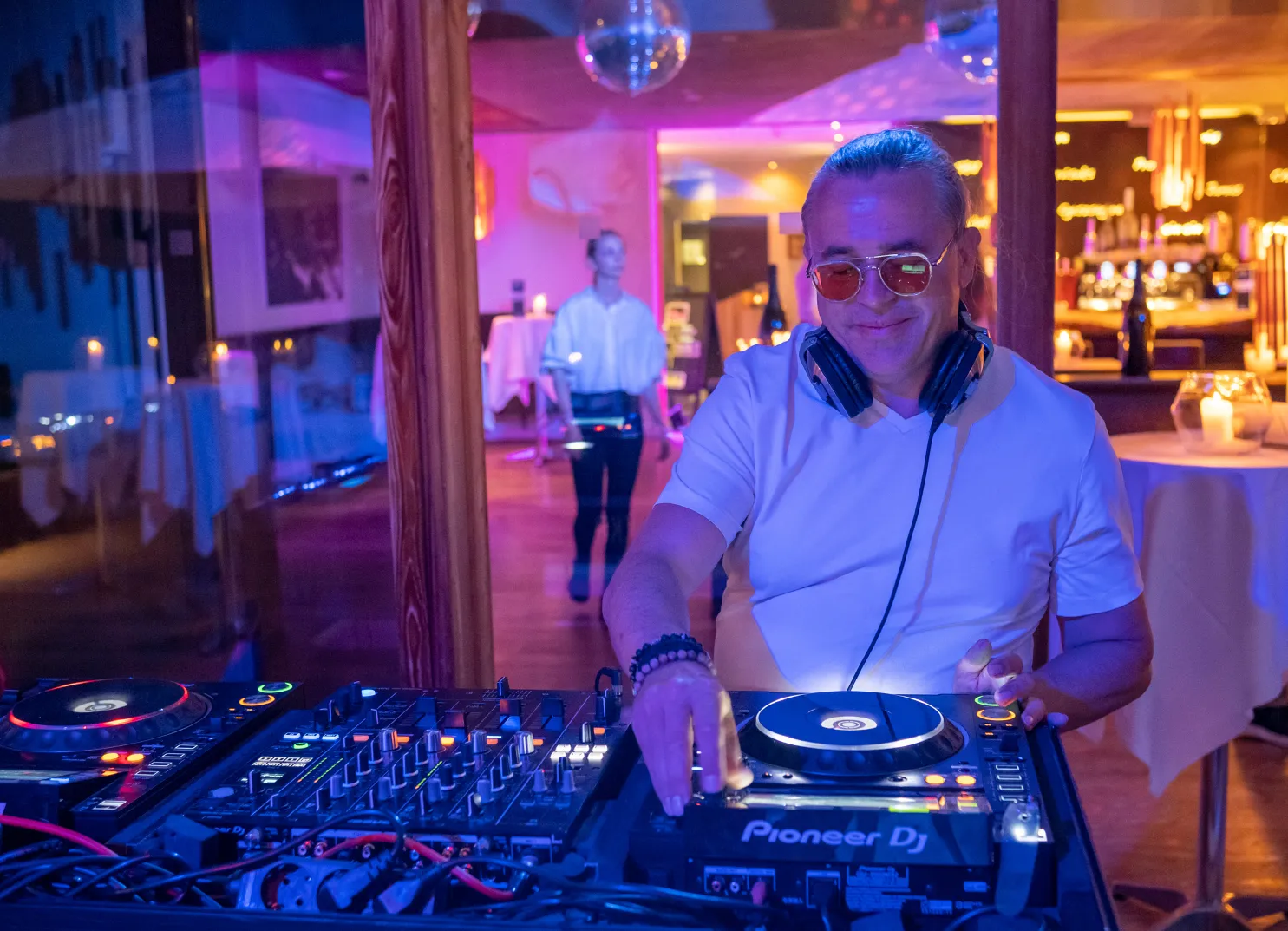 DJ with headphones at a mixing desk in an event space