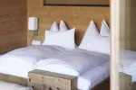 gemütliches Schlafzimmer mit Holzwand und weißer Bettwäsche