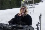 Person mit Kopfhörern an einem DJ-Setup in verschneiter Landschaft