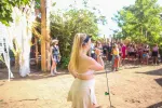 Frau auf der Bühne mit Publikum und Bäumen im Hintergrund