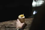 Eine Person hält ein Getränk mit einer Zitronenscheibe an einer Bar.