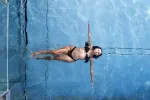 Person swimming underwater in a blue pool