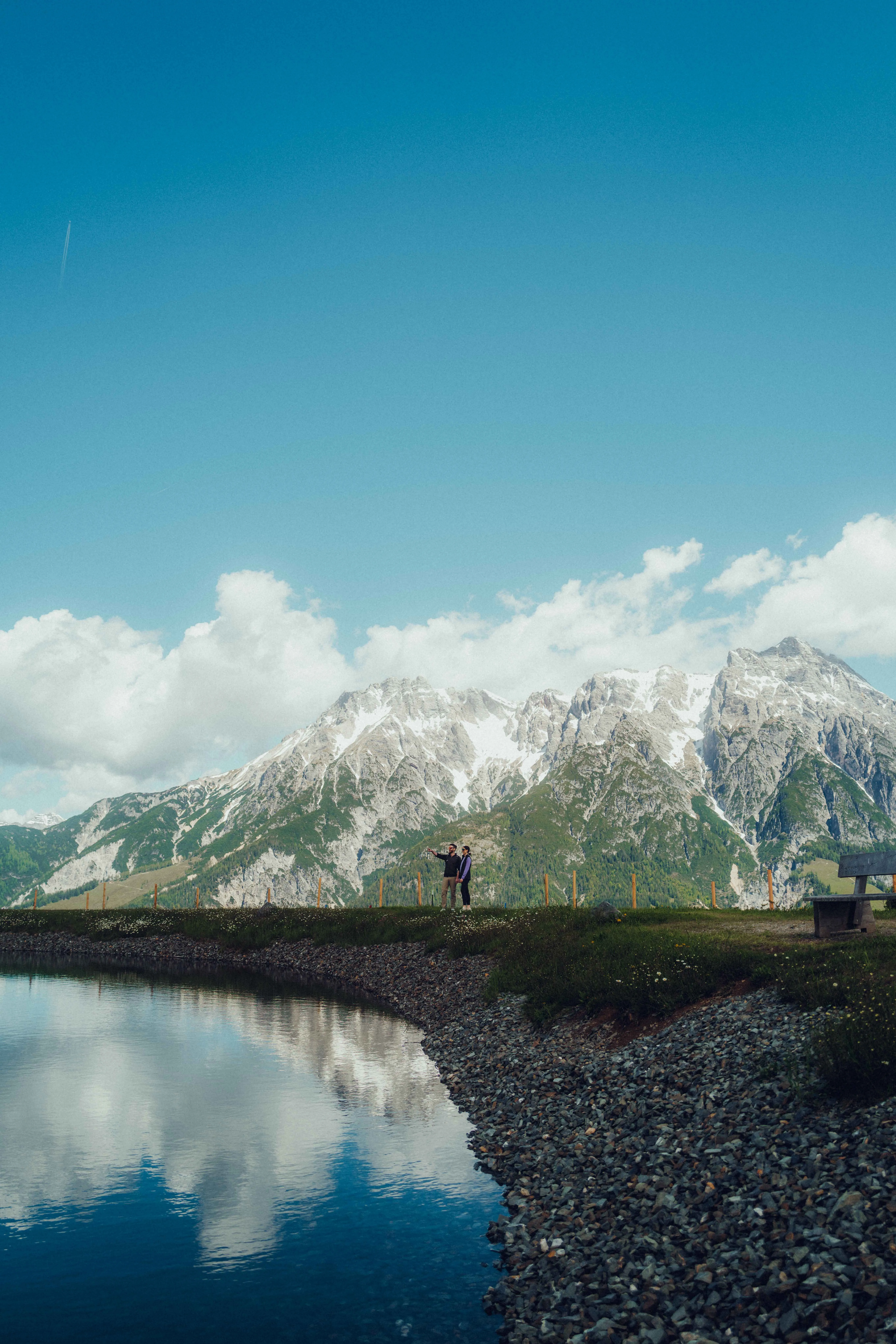 Paar steht am Ufer eines Sees mit Bergen im Hintergrund