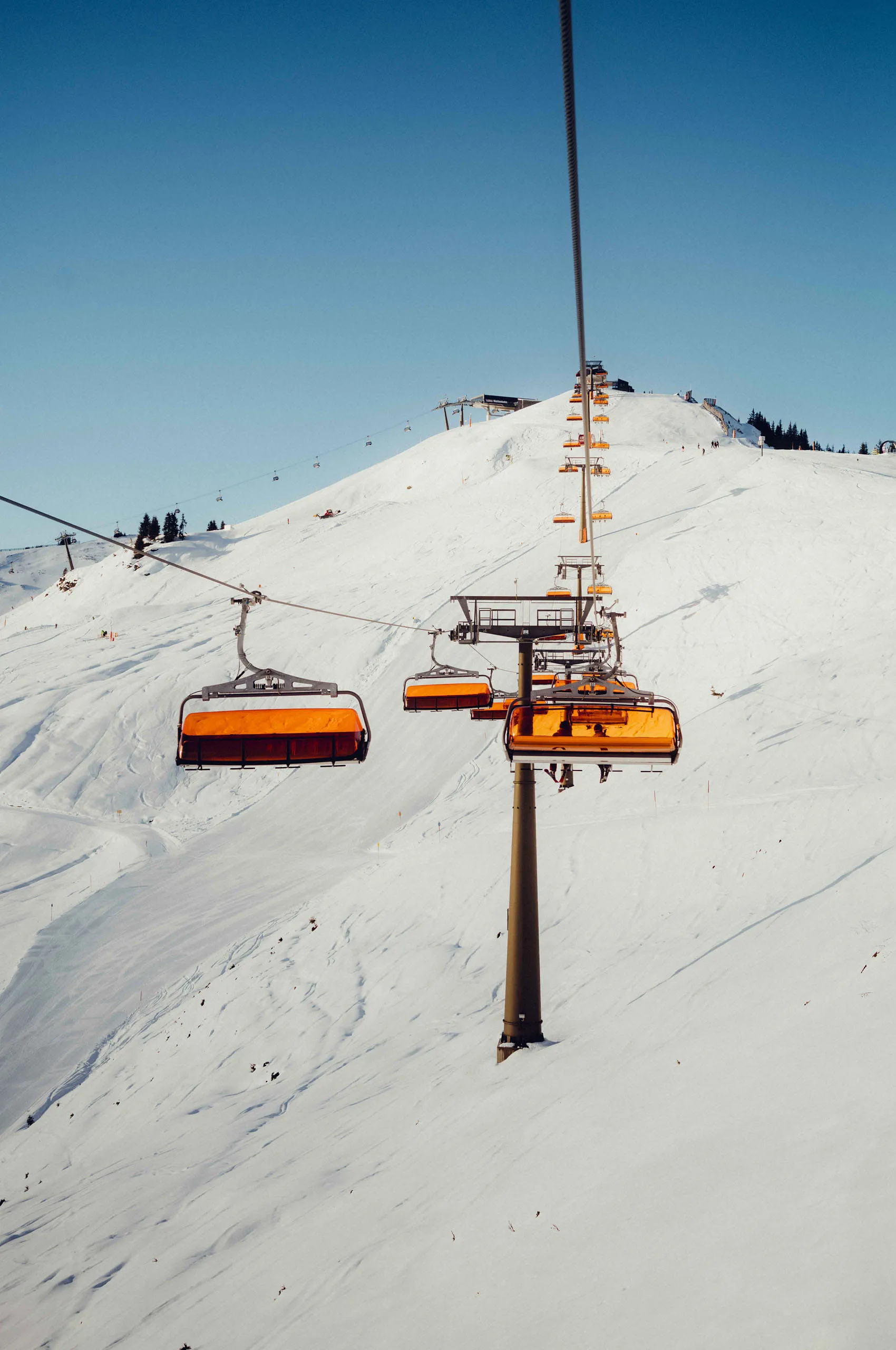 Blick auf einen Skilift mit orangen Sesseln in den verschneiten Bergen