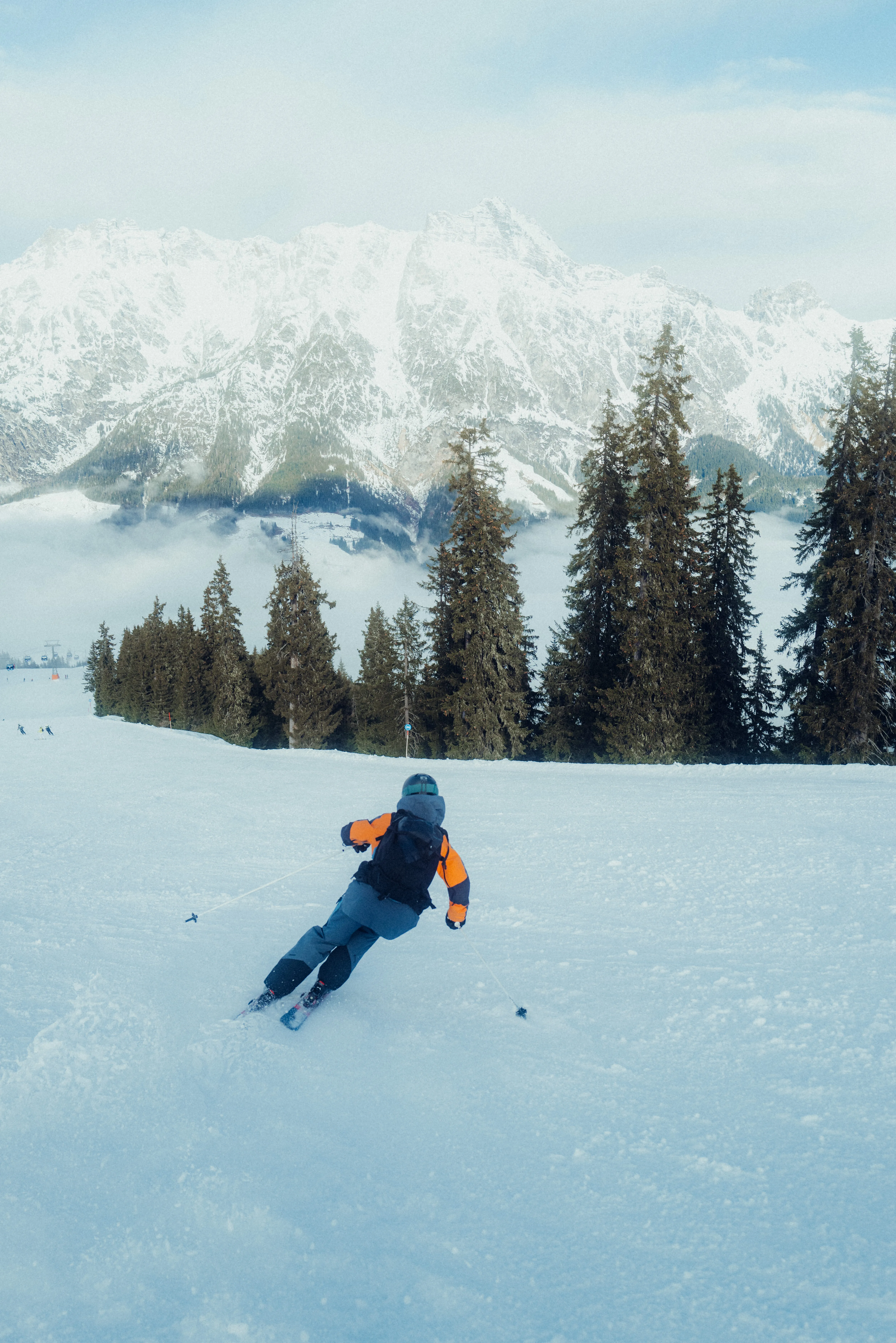 Skifahrer in Leogang vor schneebedeckten Bergen und Bäumen