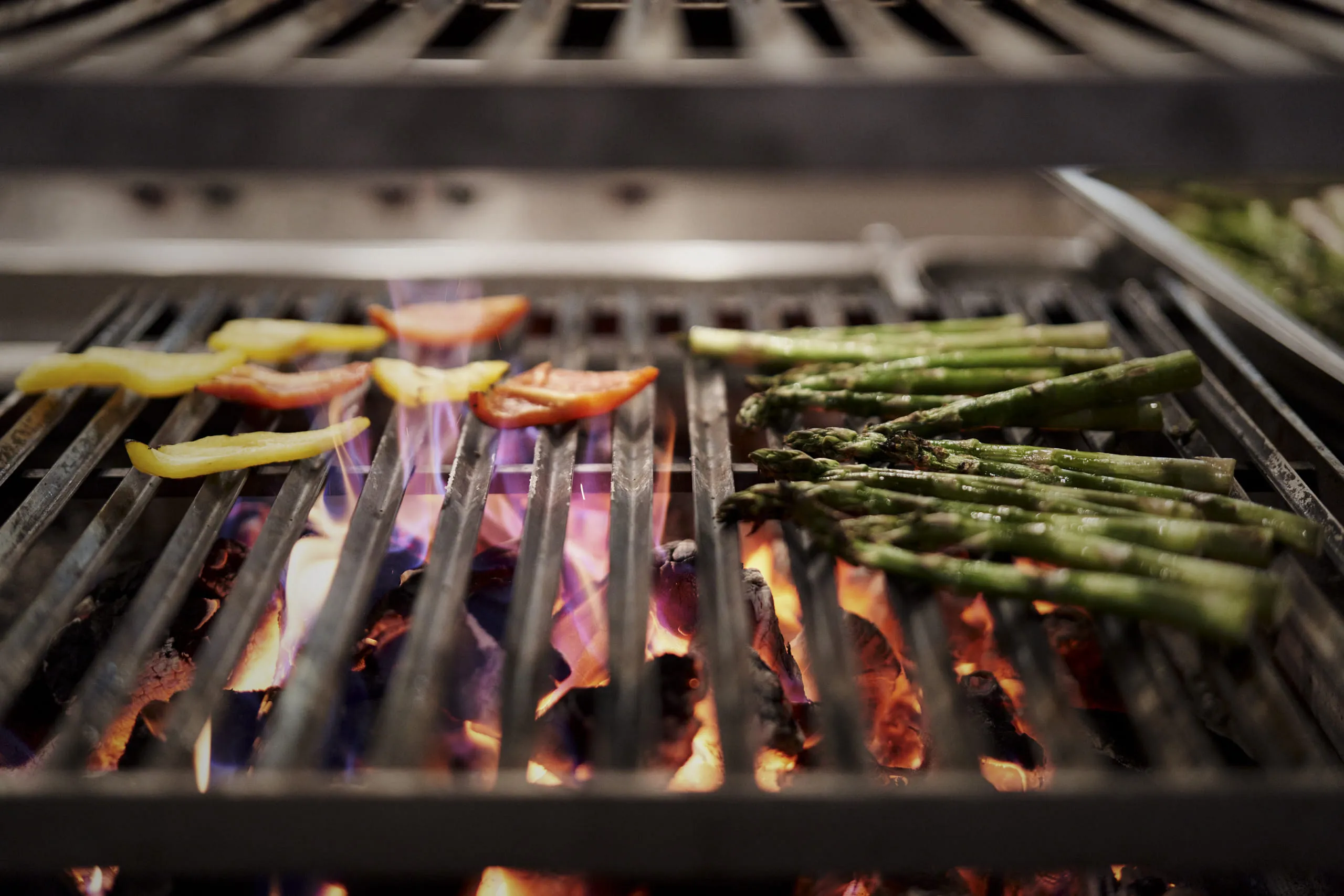 Vegetables are being grilled over open flames.