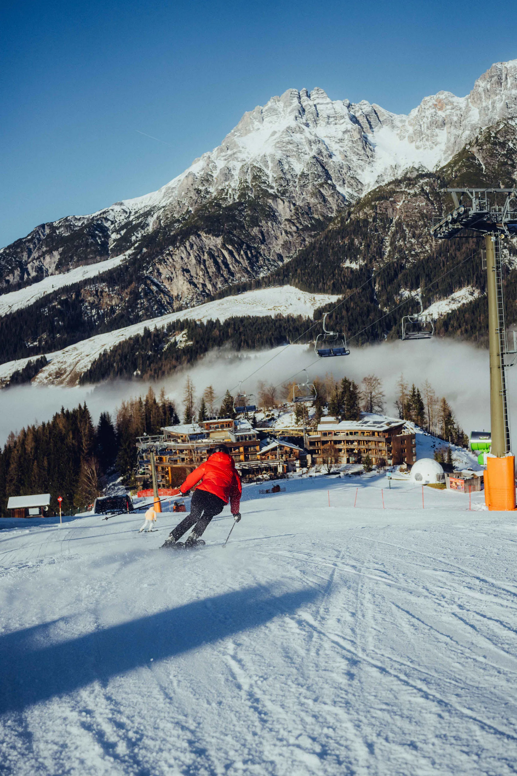 Skifahrer auf der Piste mit Aussicht auf Leogang, Berge und Nebel.