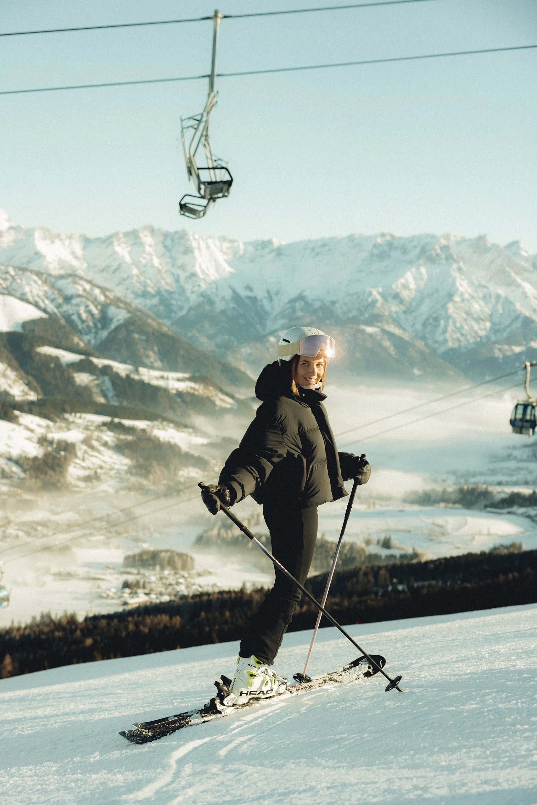 Skifahrer auf einer Piste mit Berglandschaft und Gondelbahn im Hintergrund