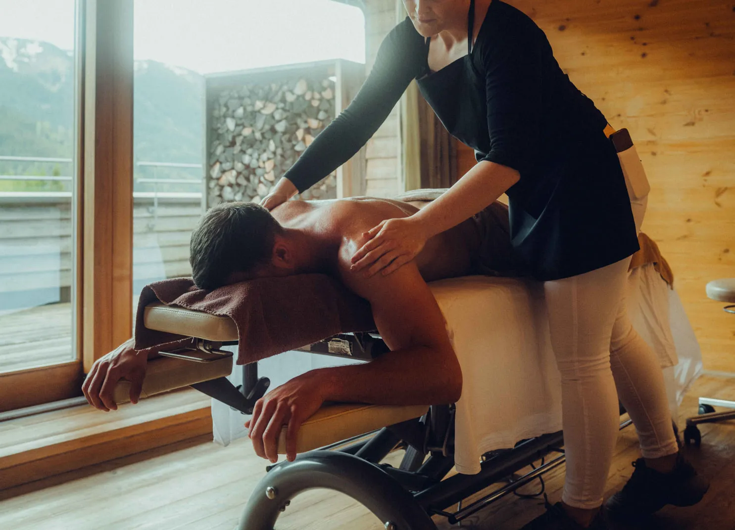 Mann erhält Massage in einem modernen Spa-Bereich mit Aussicht auf die Berge.