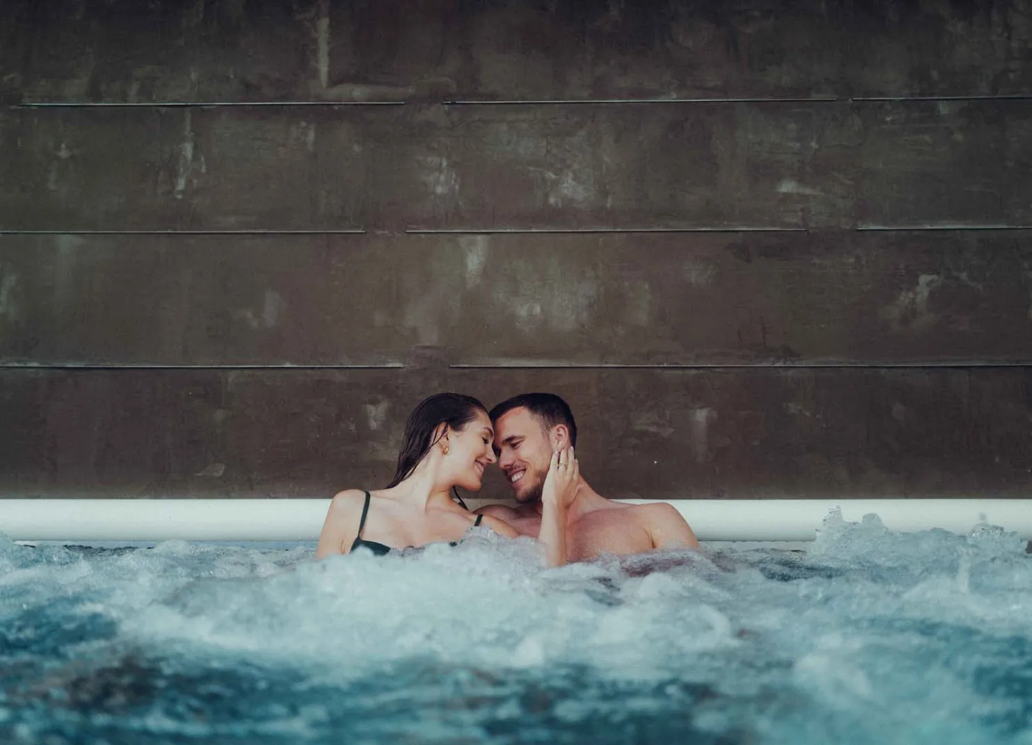 Paar im Pool, Wasser spritzt, intime Atmosphäre