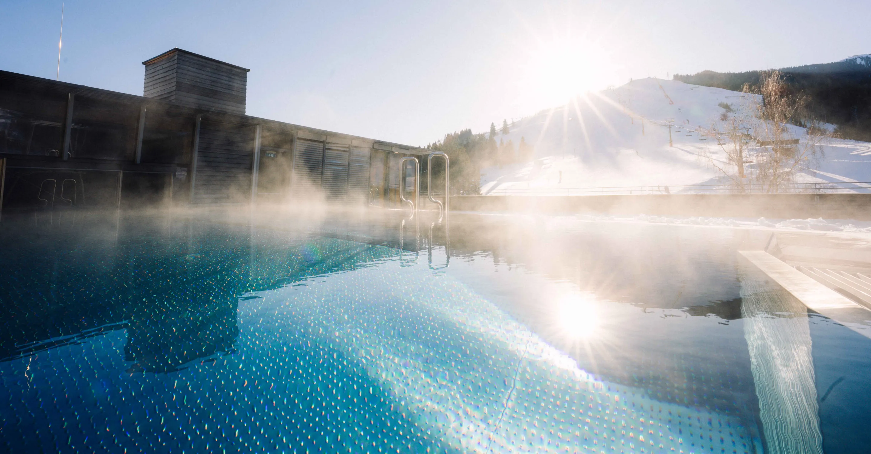 Schwimmbad mit Dampf und Bergen im Hintergrund