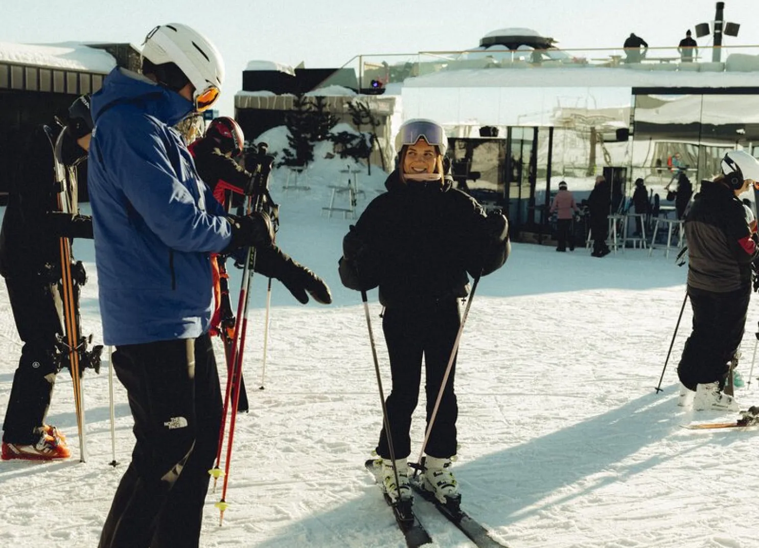 Skifahrer auf einer verschneiten Piste, einer lächelt im Vordergrund, andere im Hintergrund