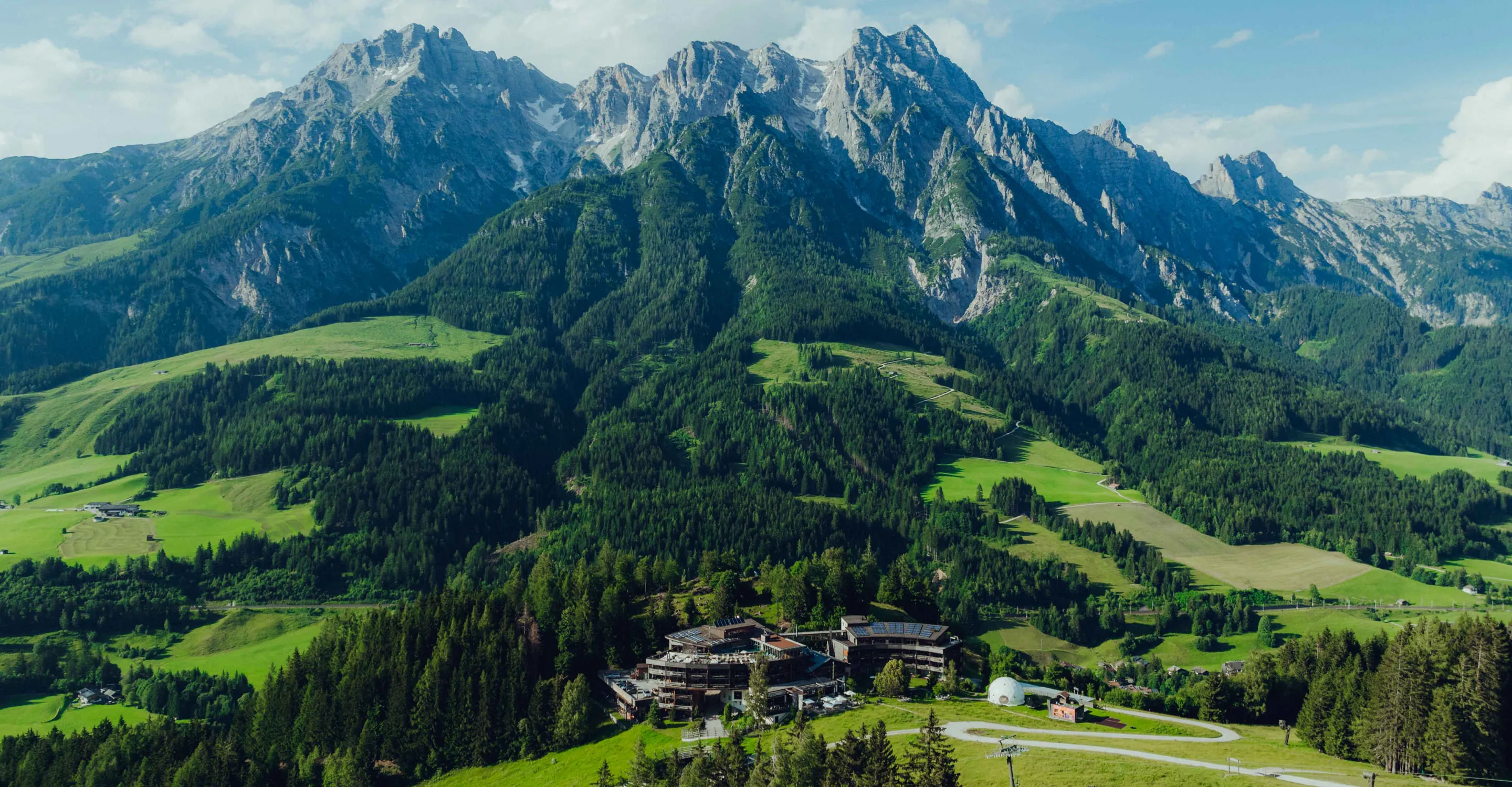 Blick auf Berge und grüne Täler mit einer Ansiedlung im Vordergrund