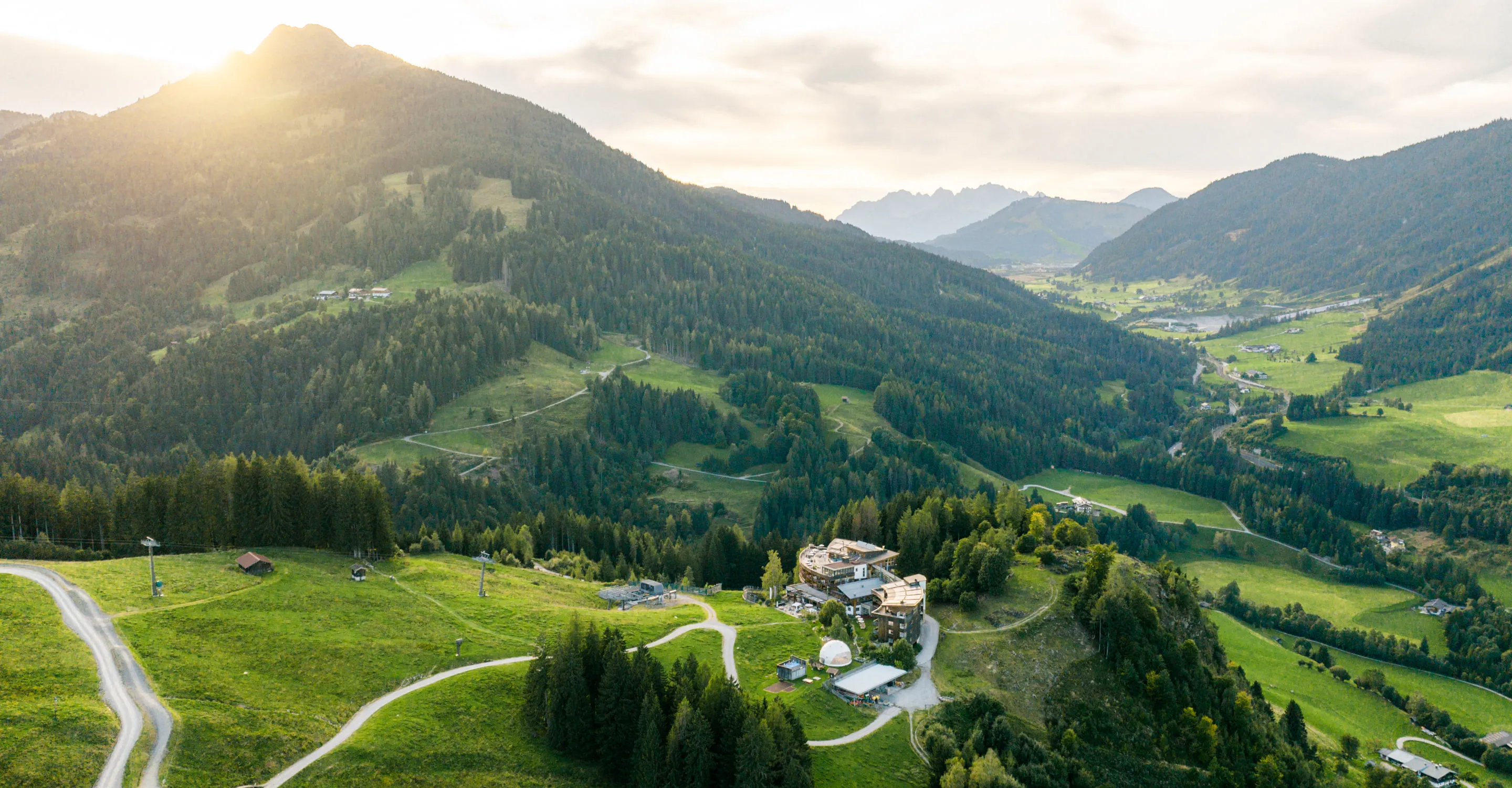 Blick auf grüne Hügel und Berge mit einem Dorf im Tal.