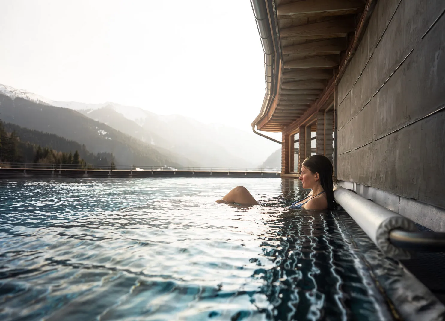 Frau im Pool vor winterlicher Kulisse