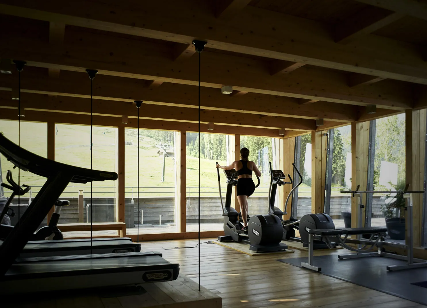 Person on an elliptical trainer in a modern gym with large windows