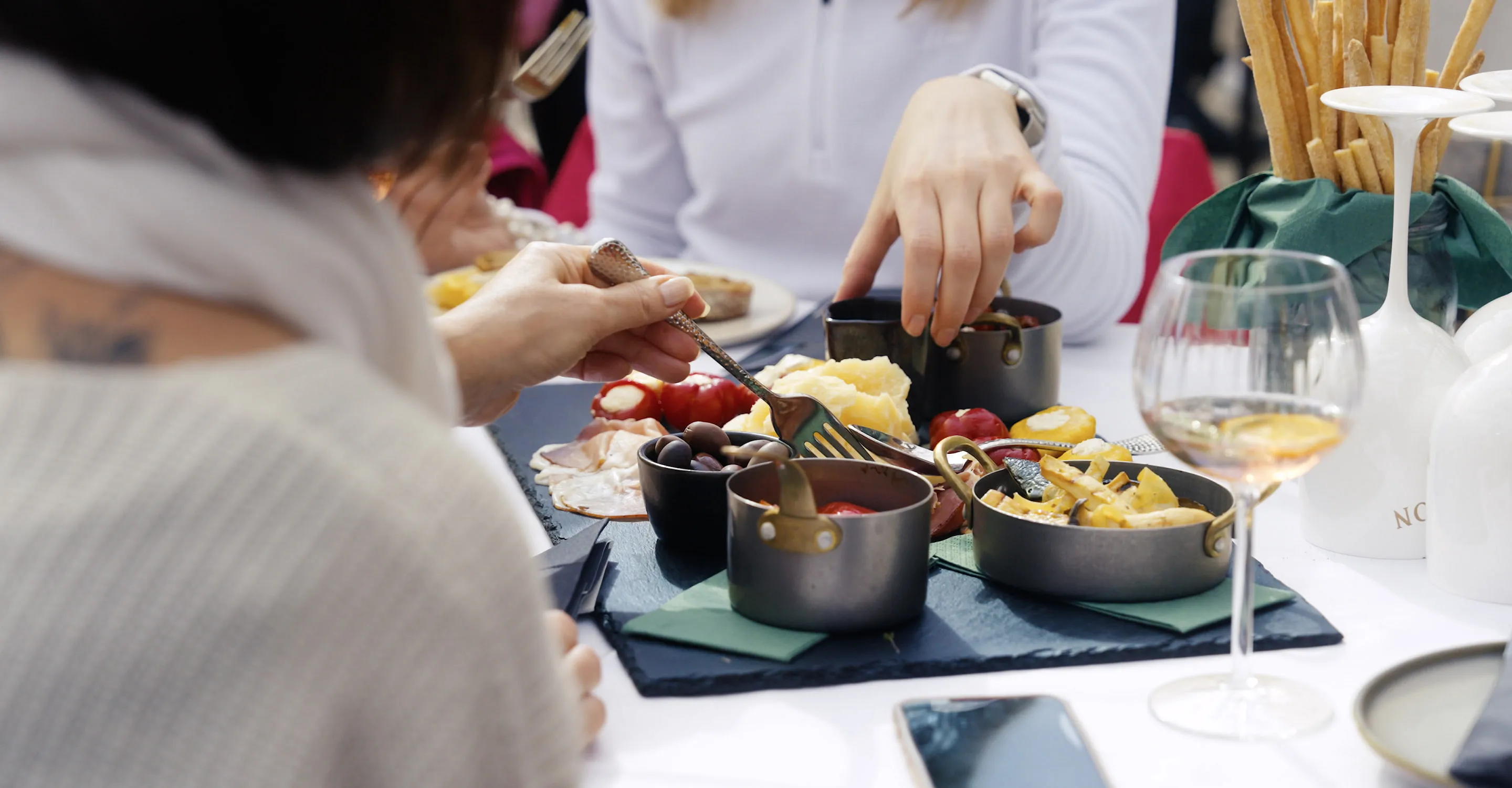 Tisch mit verschiedenen Gerichten und Getränken, Hände greifen nach Essen