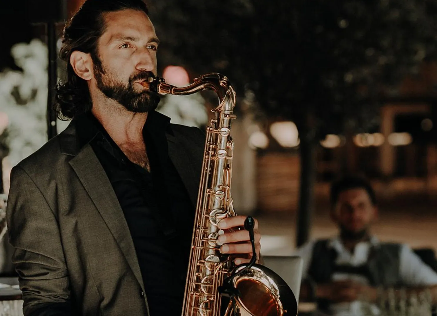 A man playing a saxophone in a stylish setting at night.