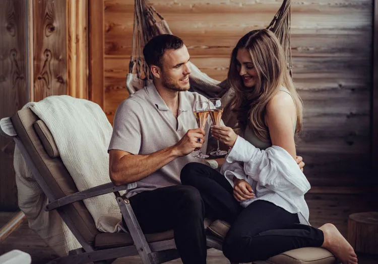 A couple drinks toast in a wooden hotel setting.