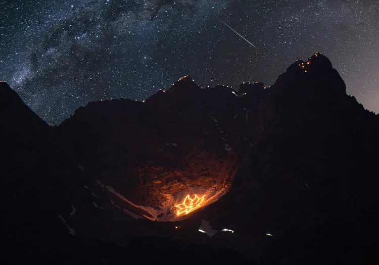 Mountains with burning flames in the valley under a starry sky
