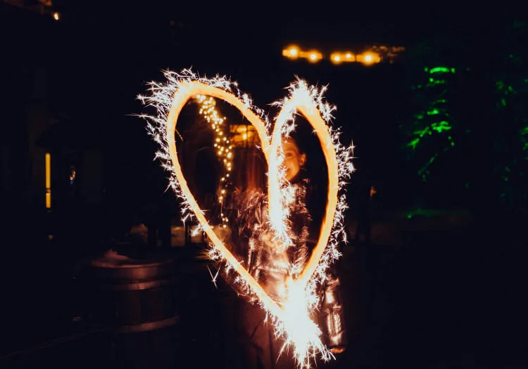 Person drawing a heart with sparklers at night.