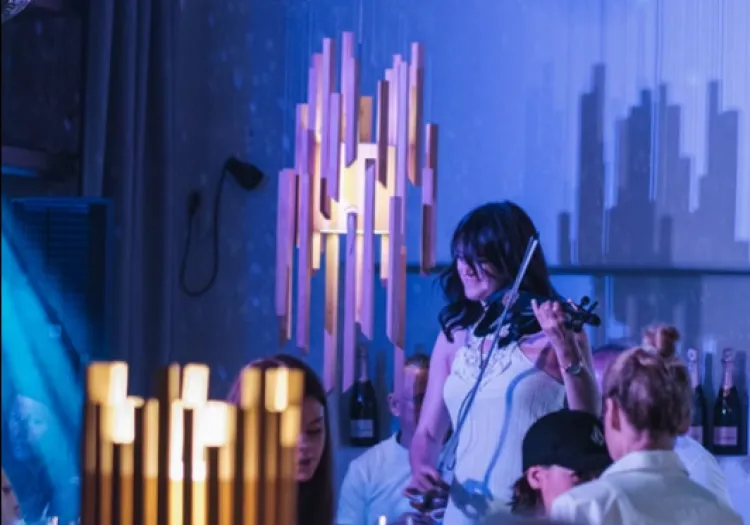 Woman playing violin in an elegant room with decorative lighting