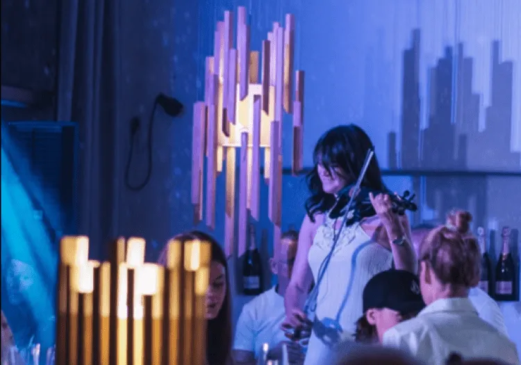 Frau spielt Geige in einem Restaurant mit modernen Lampen.