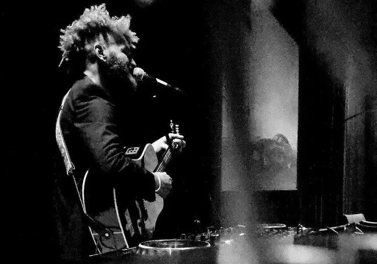 Musiker spielt Gitarre und singt auf der Bühne in Schwarzweiß