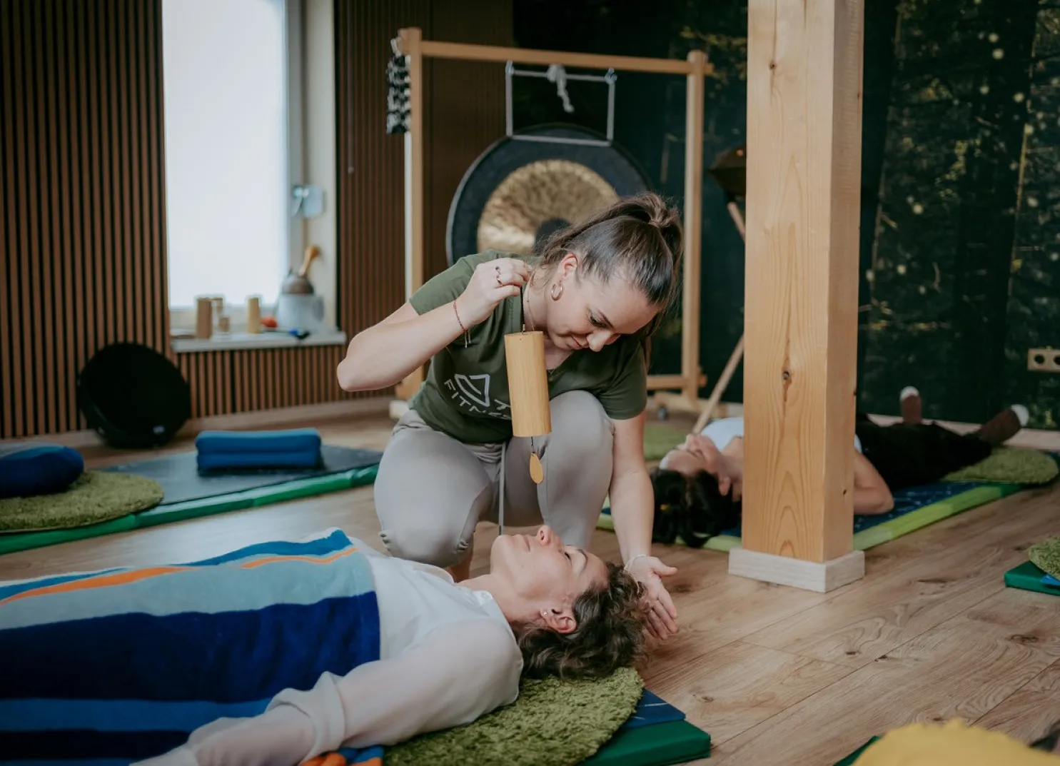 Wellness-Sitzung mit einer liegenden Person und einer anderen mit einer Klangschale