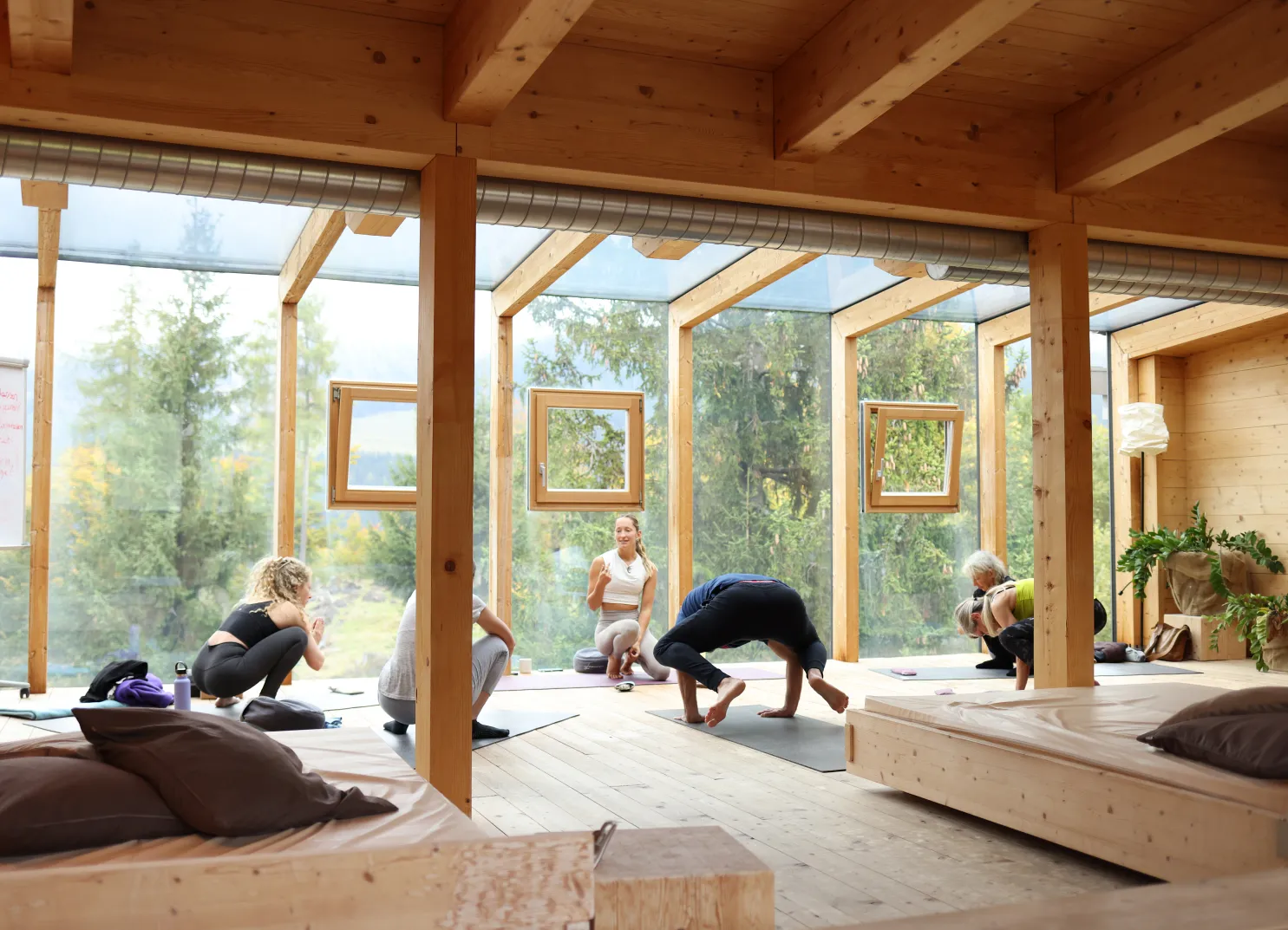 Yogaklasse in einem hellen Holzstudio mit großen Fenstern