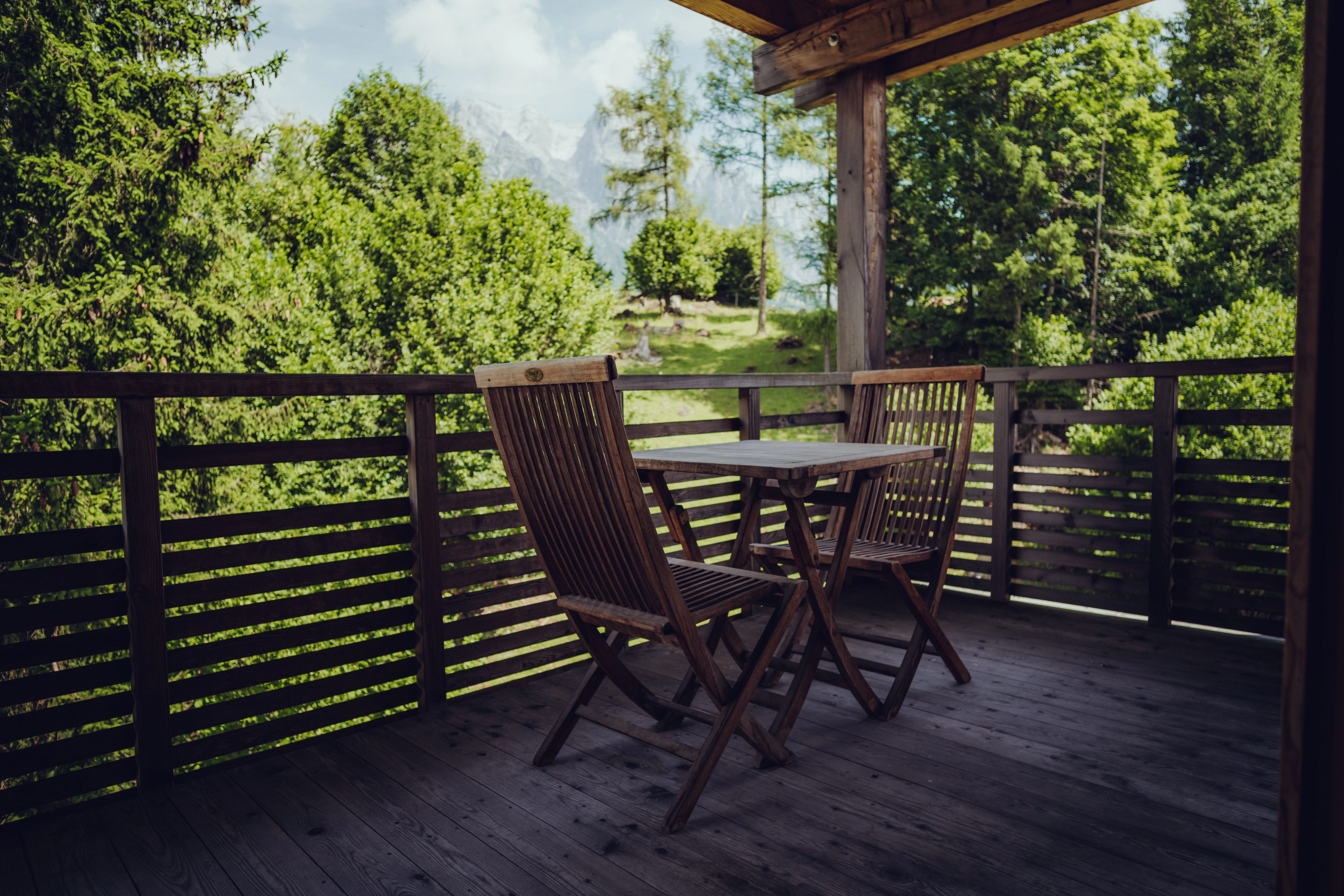 Holzbalkon mit Tisch und Stühlen mit Blick auf das Grün