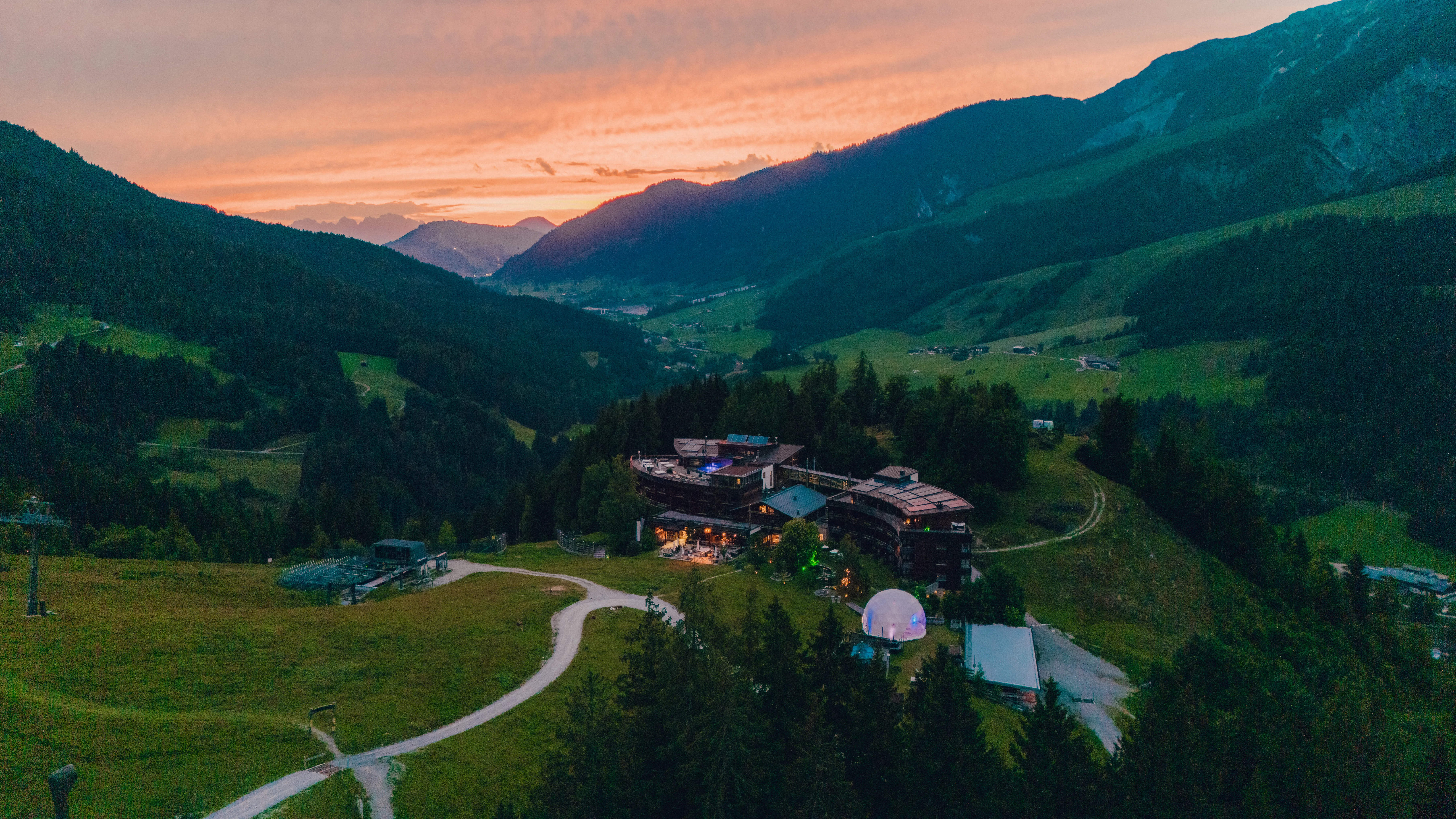 Luftaufnahme einer Berglandschaft mit einem Gebäude bei Sonnenuntergang