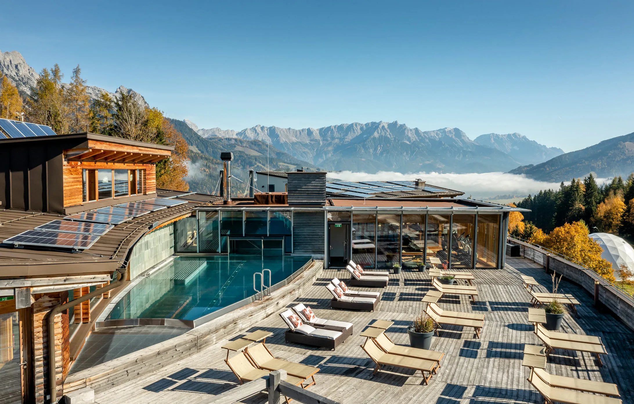 Moderne Terrasse mit Pool und Liegen, Blick auf die Berge und Nebel.