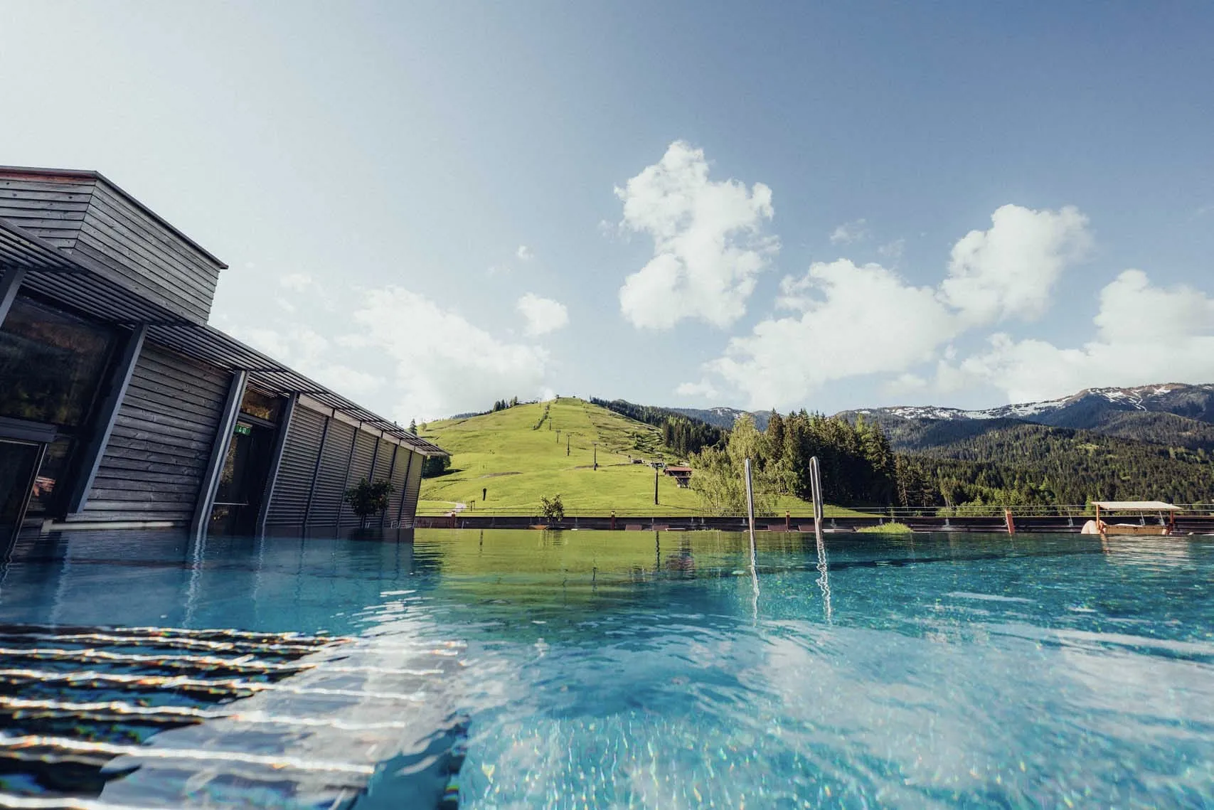 Pool mit Blick auf eine grüne Hügel- und Berglandschaft