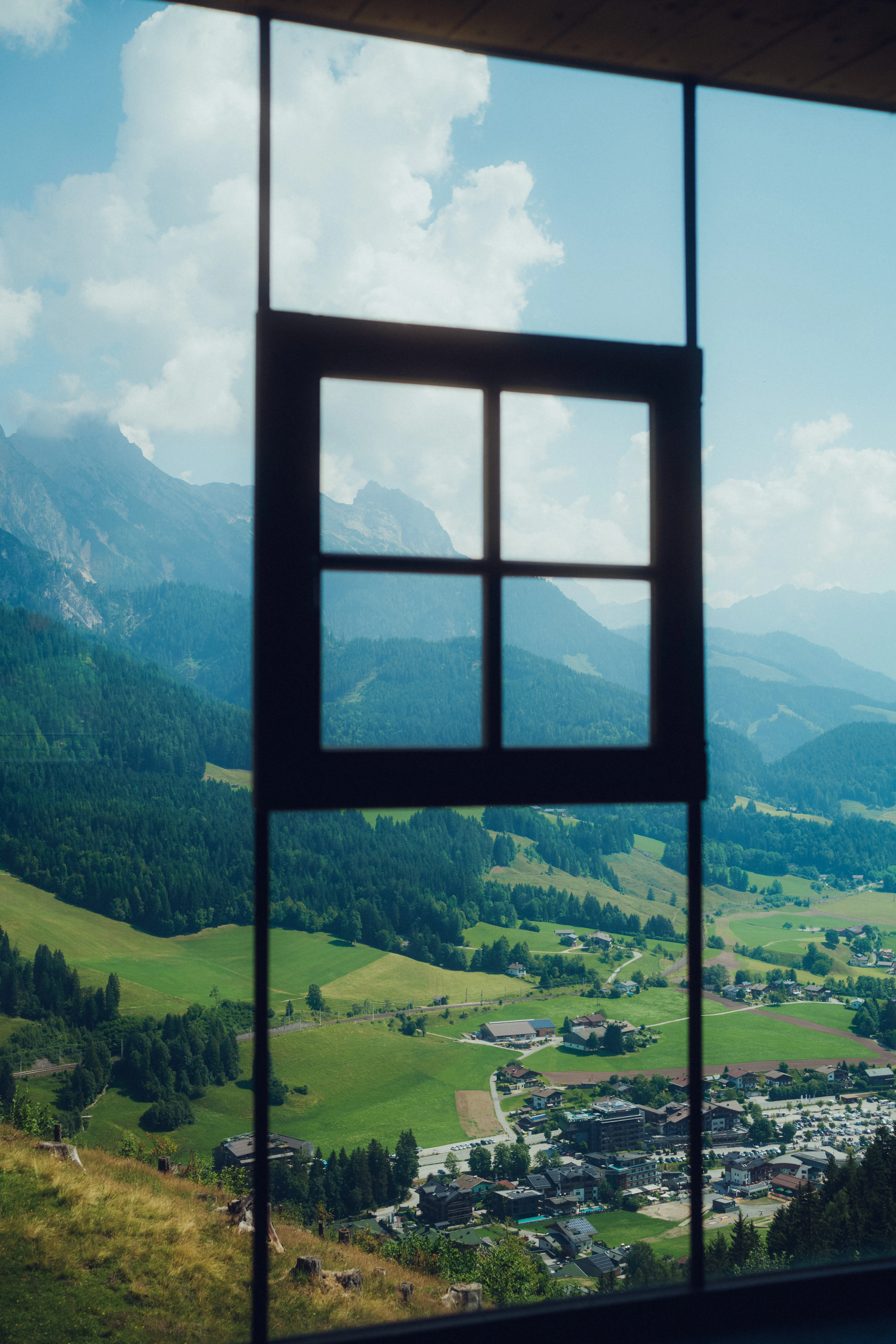 Aussicht durch ein Fenster auf hügelige Landschaften und Berge
