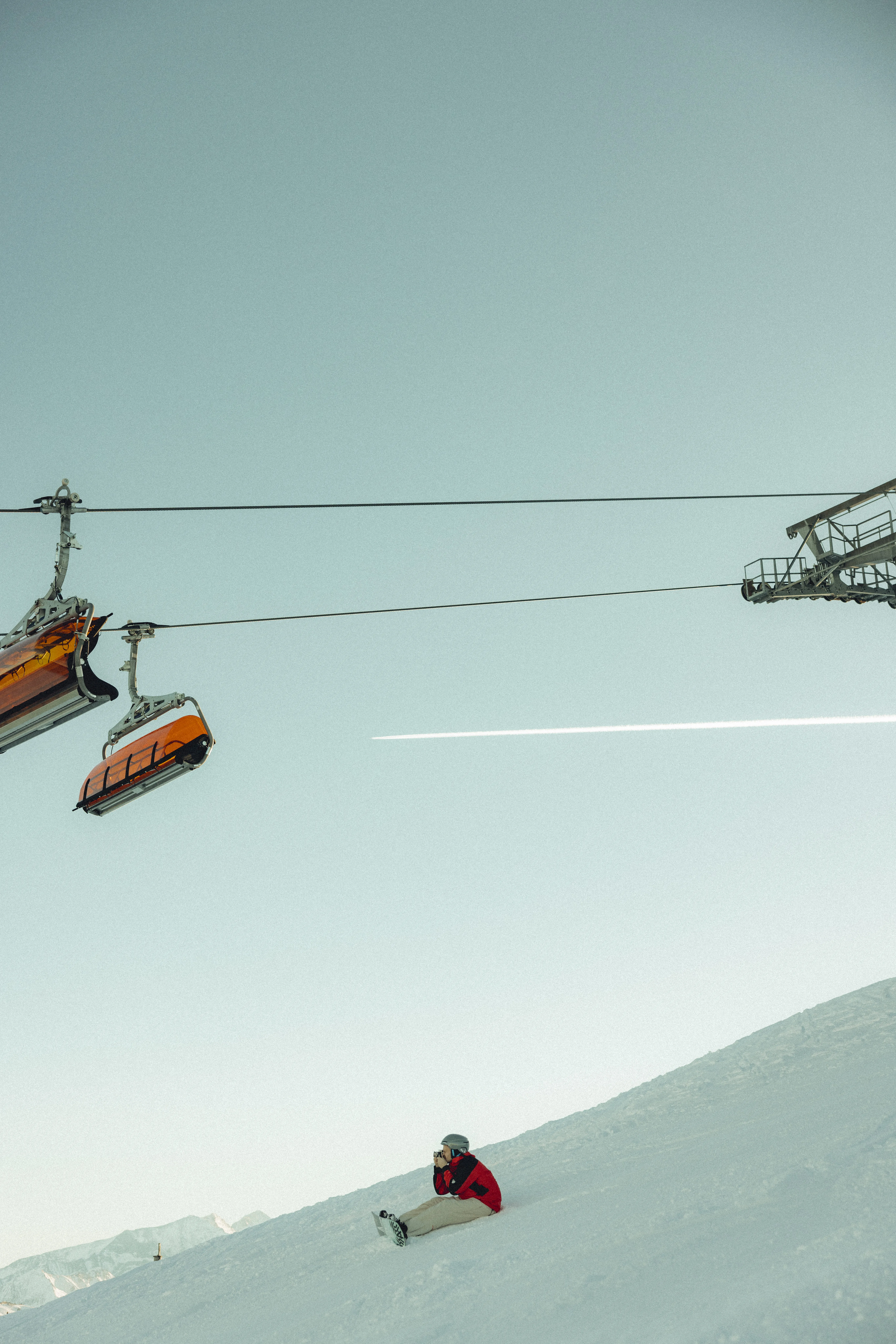Skilift über schneebedecktem Hang mit Person im Vordergrund