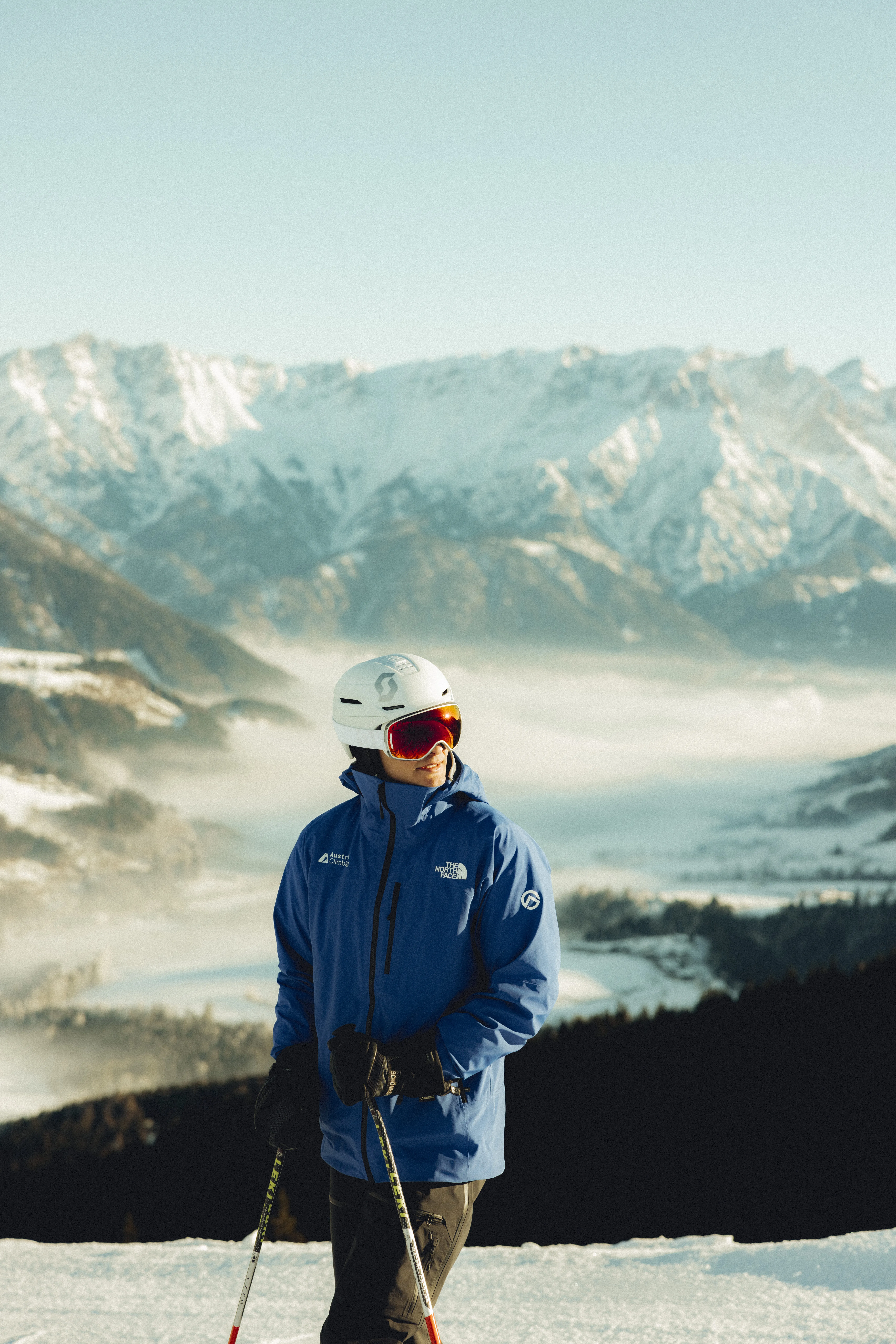 Skifahrer in blauer Jacke vor verschneiten Bergen und Tal