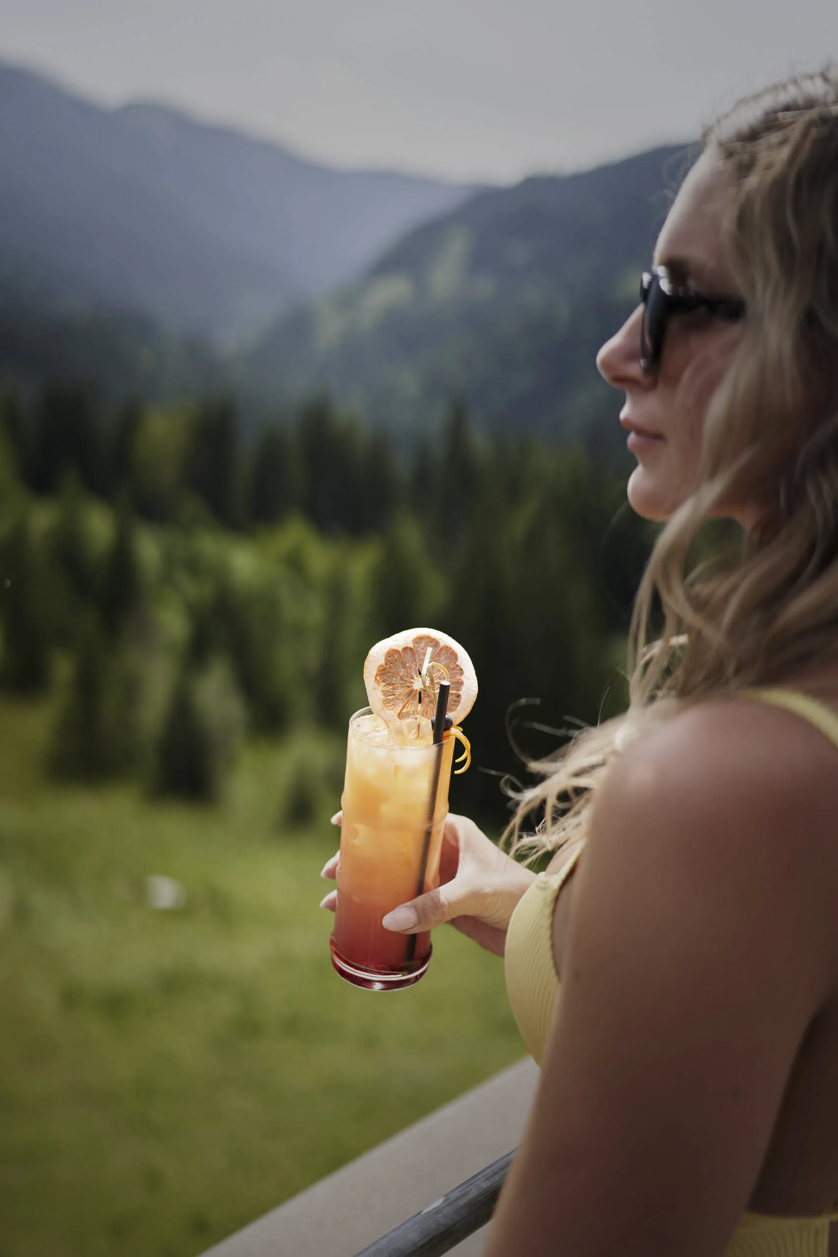 Woman holding a drink with mountains in the background