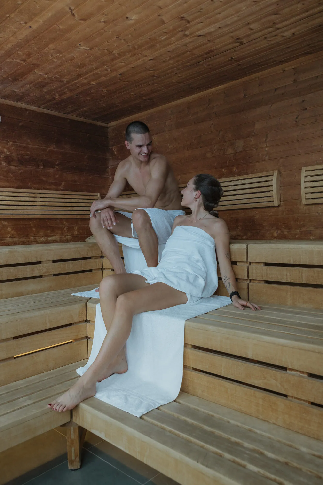 couple relaxing in a sauna on wooden benches