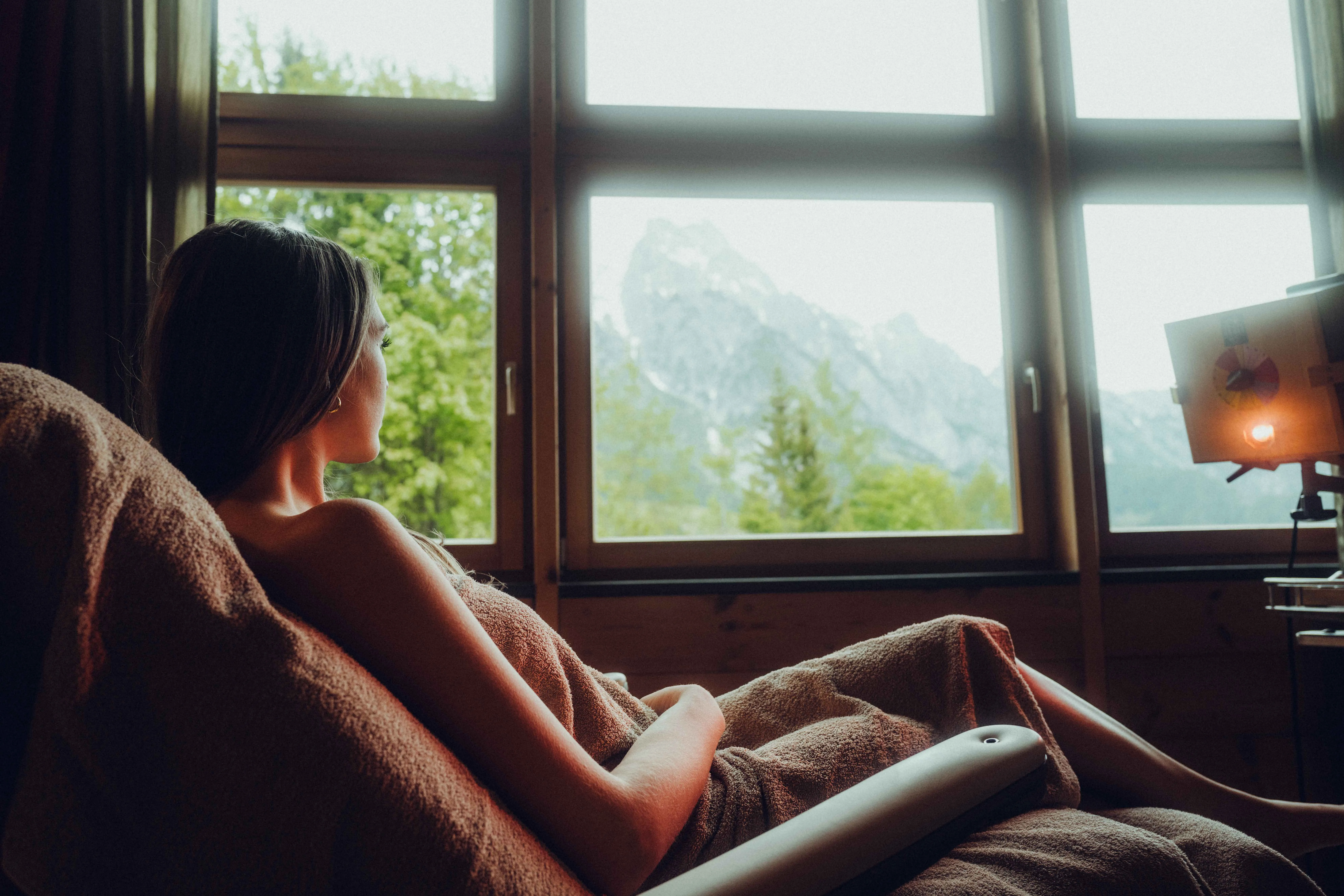 Woman relaxing in a chair with mountain view through a window