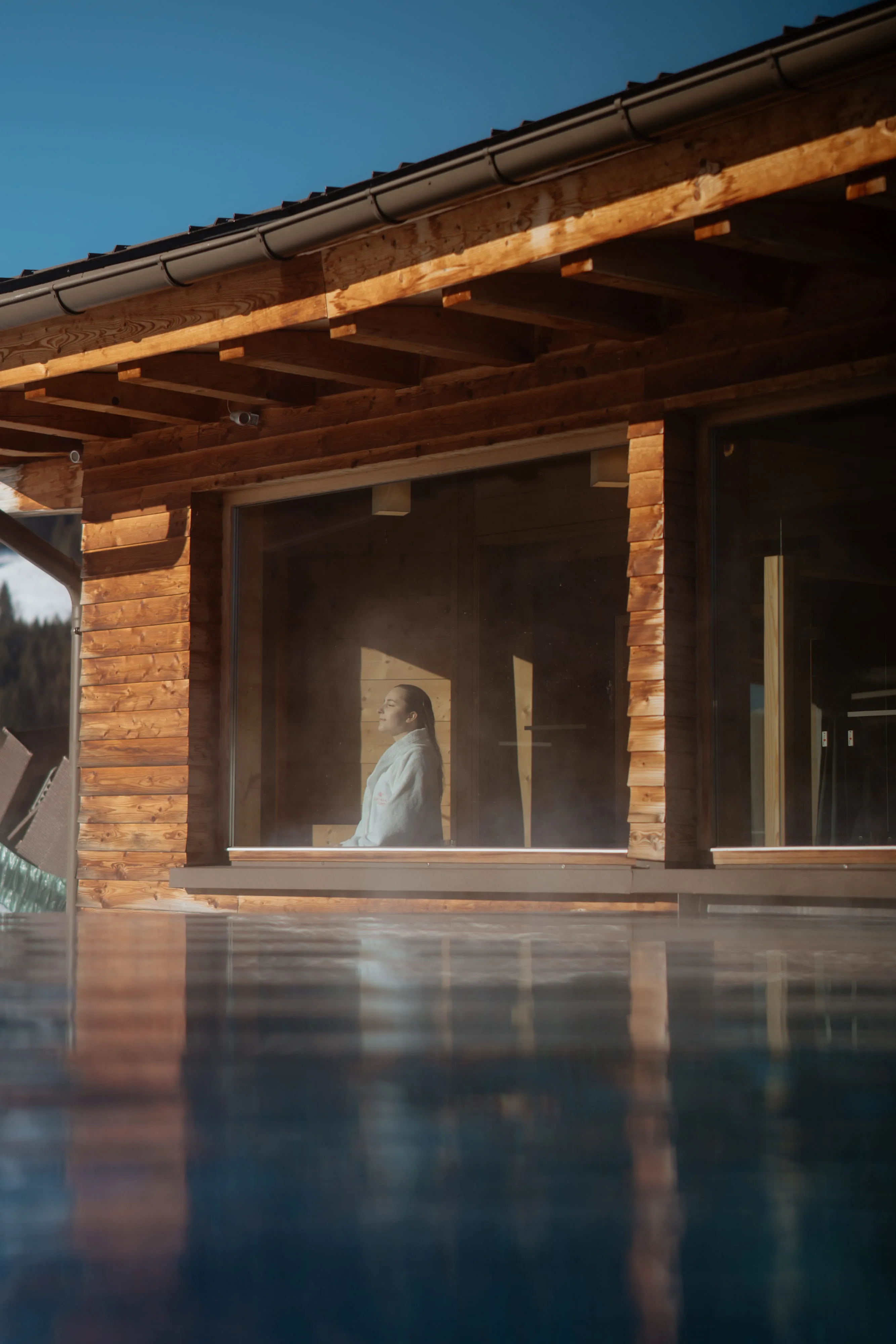 Person in a robe inside a wooden structure with large windows