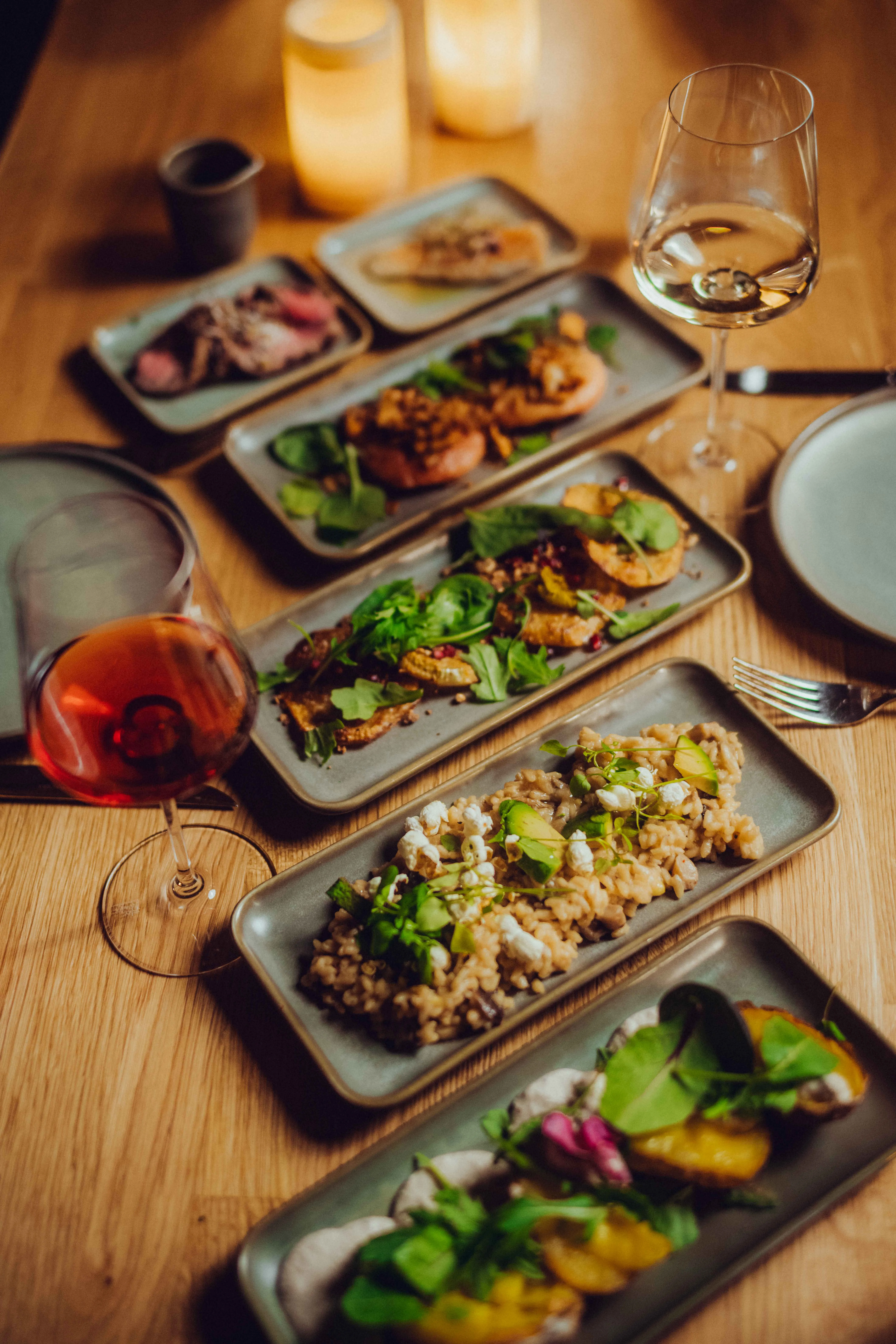 Table with various gourmet dishes and wine glass.