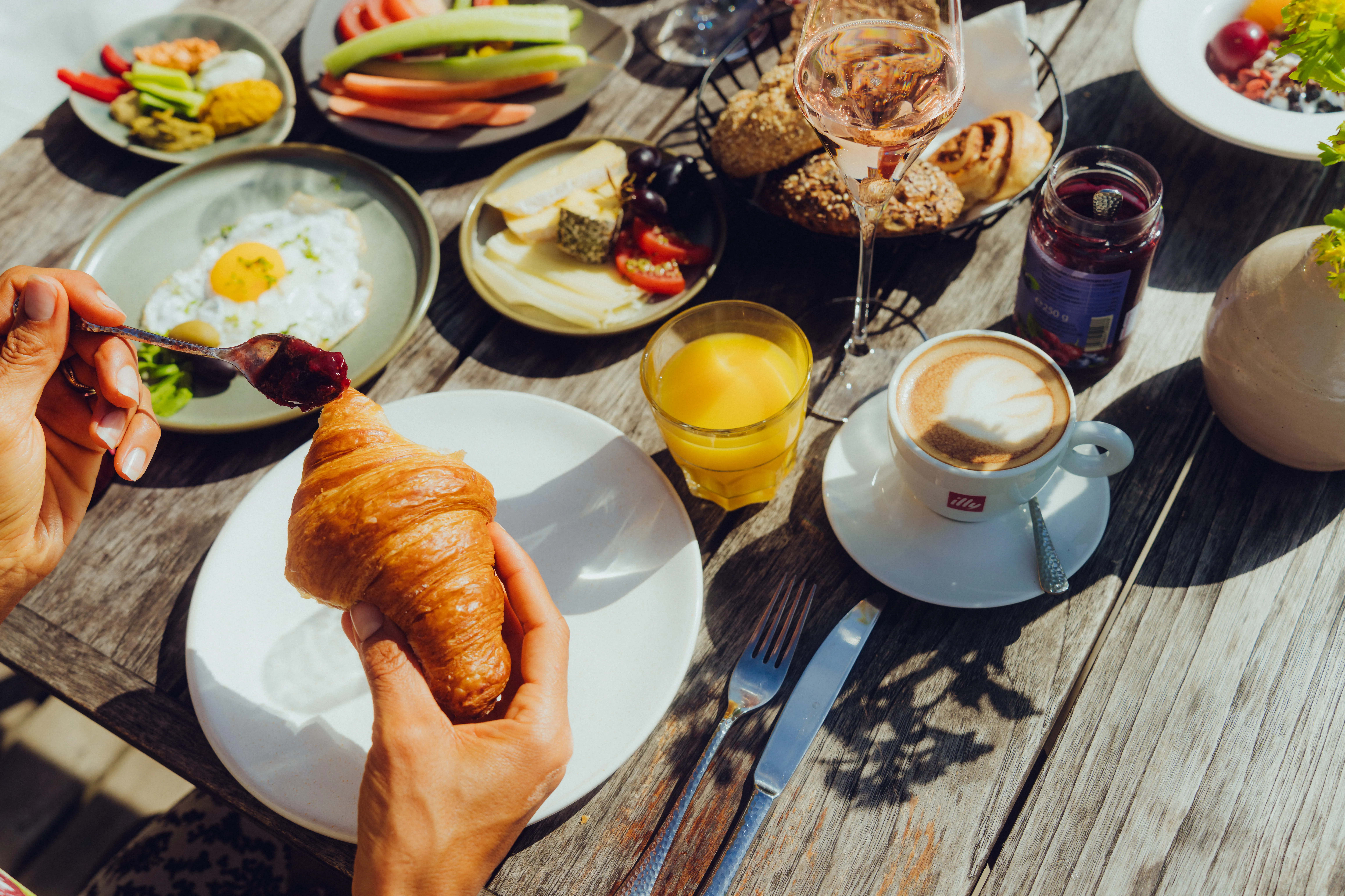 Croissant with jam and a drink on a breakfast table.