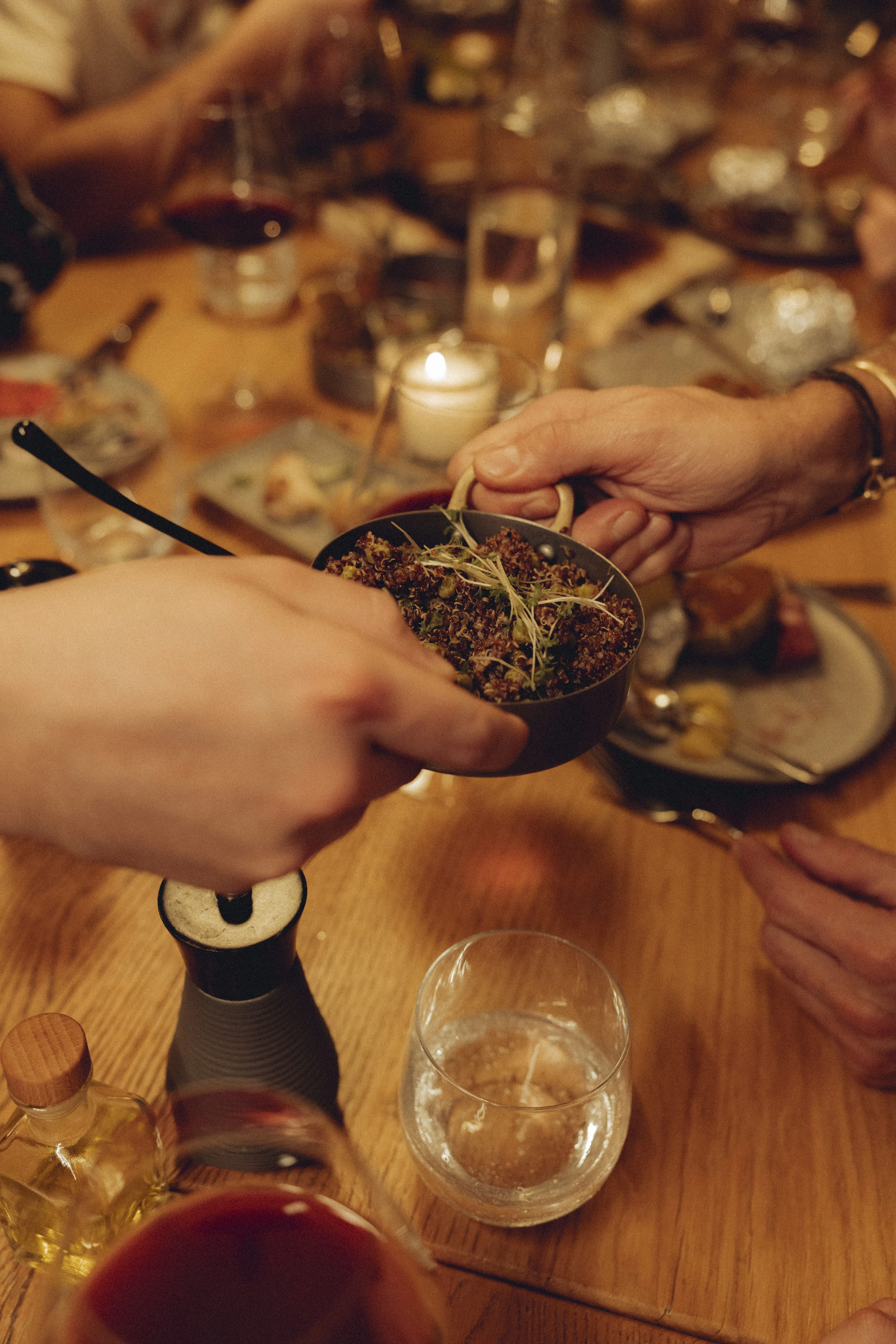 Hands passing a bowl of herbs at a dining table
