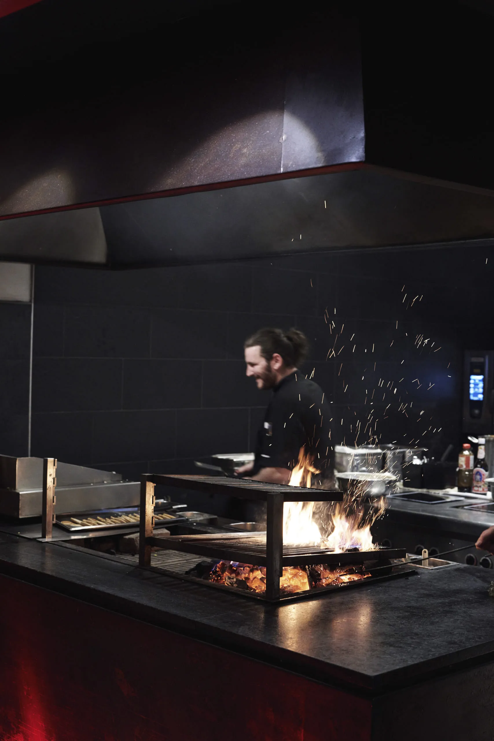 Chef in a modern kitchen area with an open flame