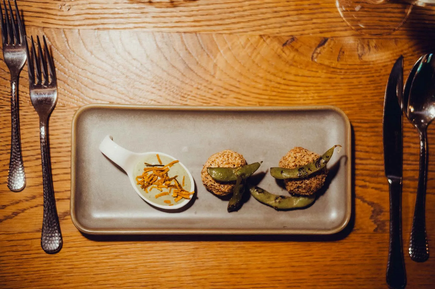 A plate with two round dishes and a small bowl with garnish.