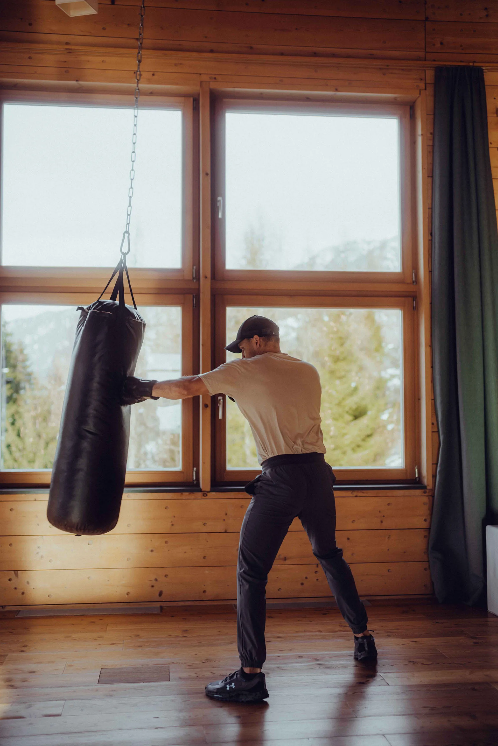 Man training with a punching bag in a wooden hotel setting.
