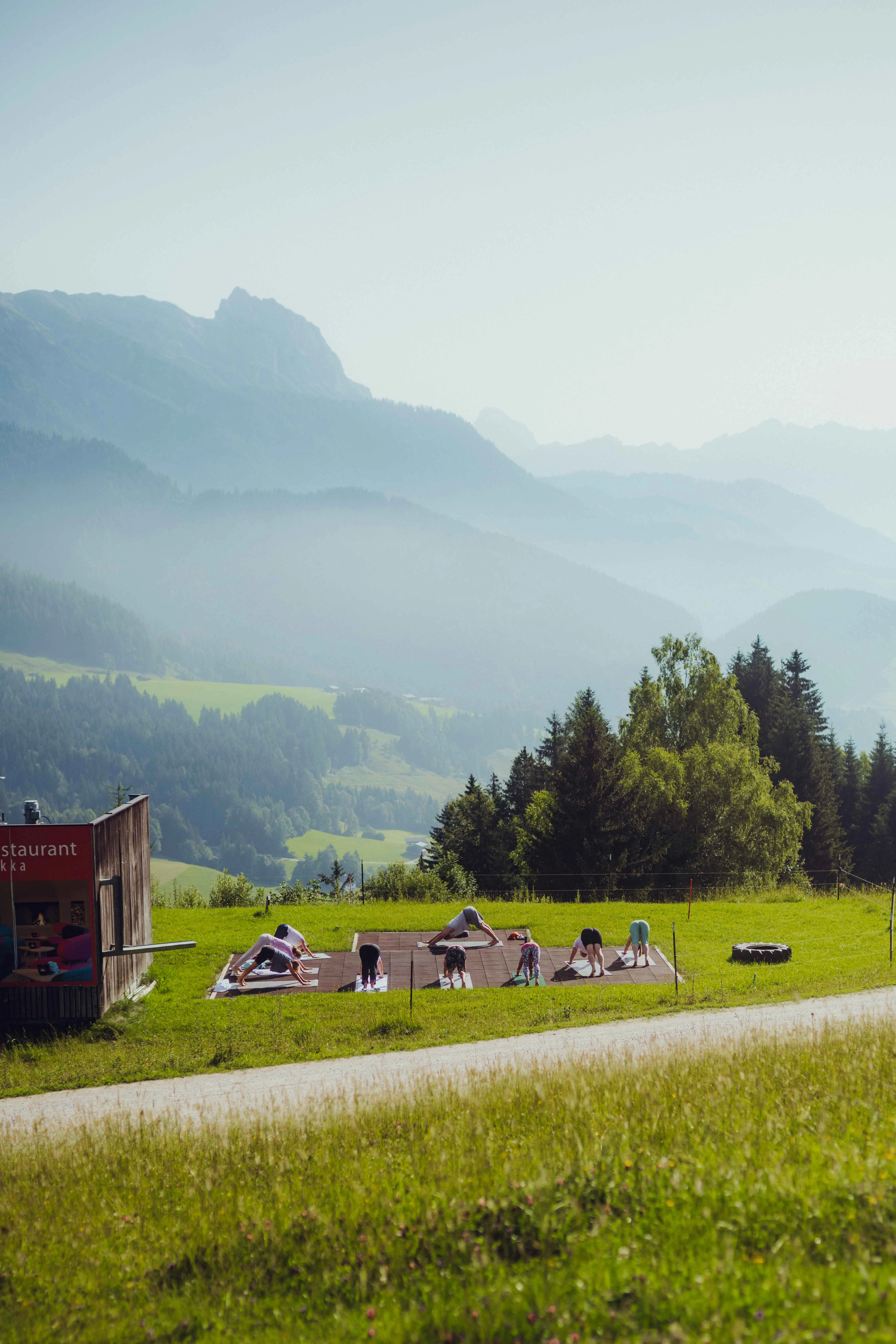 People relaxing on a meadow with mountains in the background.