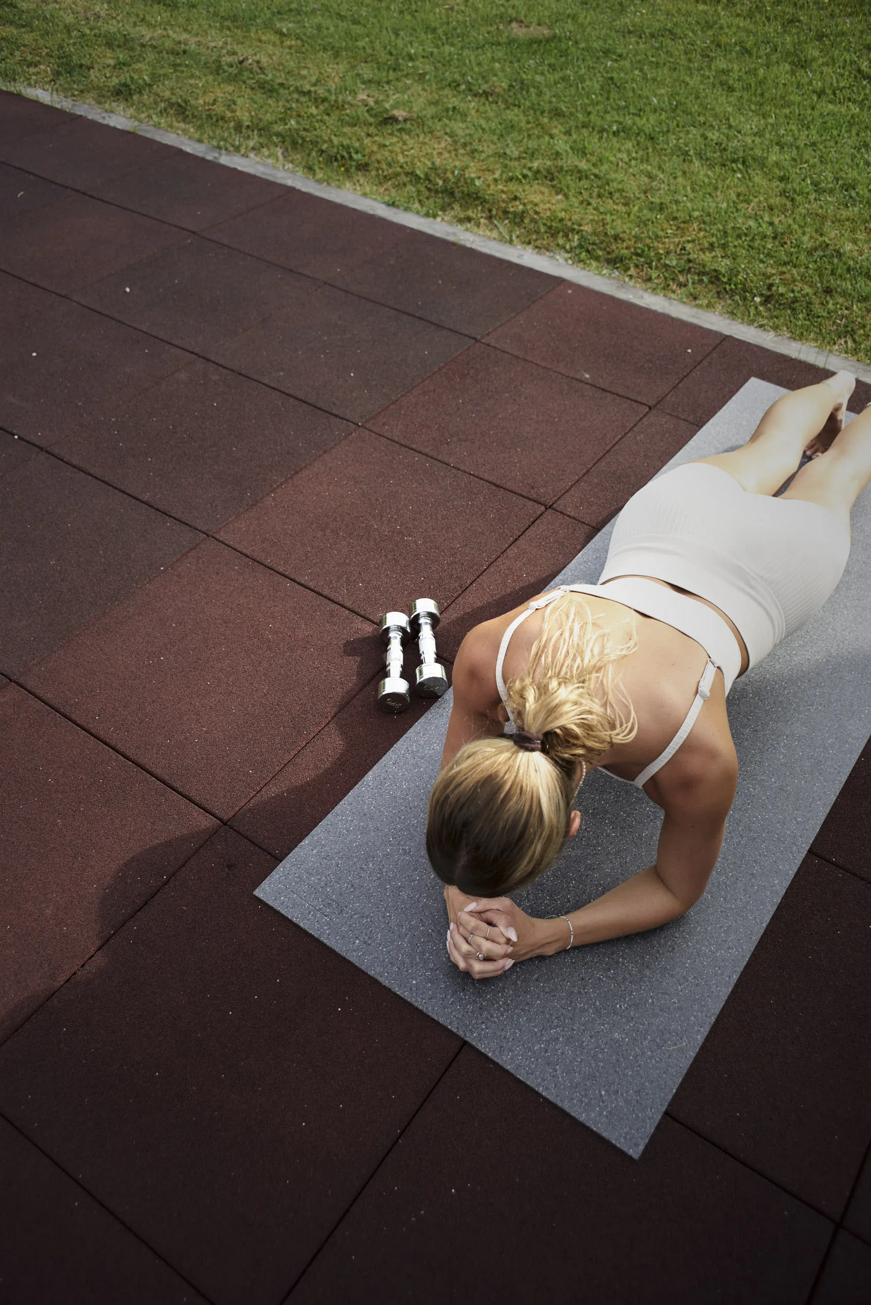 A person performing a plank on a mat with weights beside them.