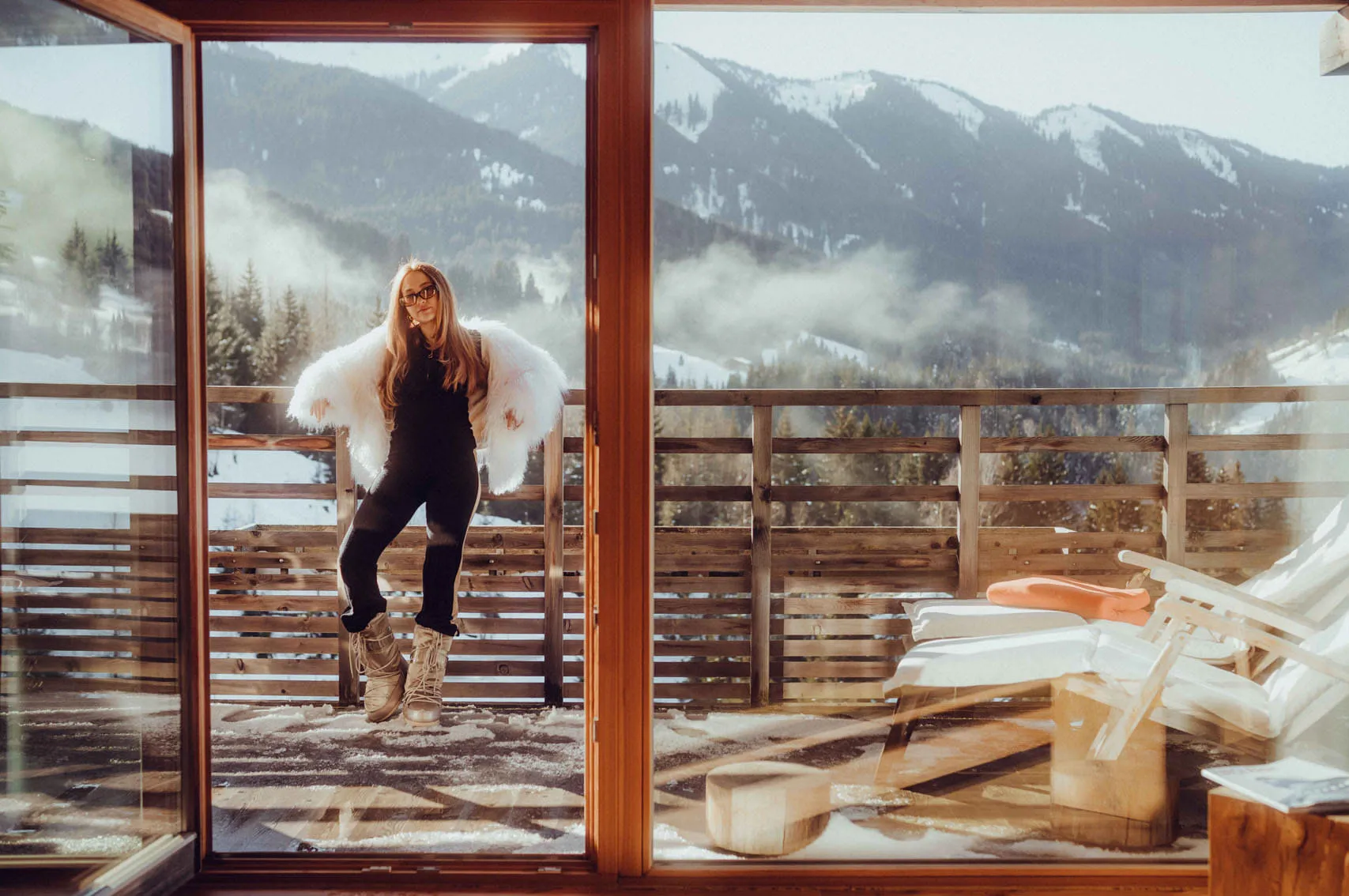 Woman in winter attire on balcony with mountain view in Leogang
